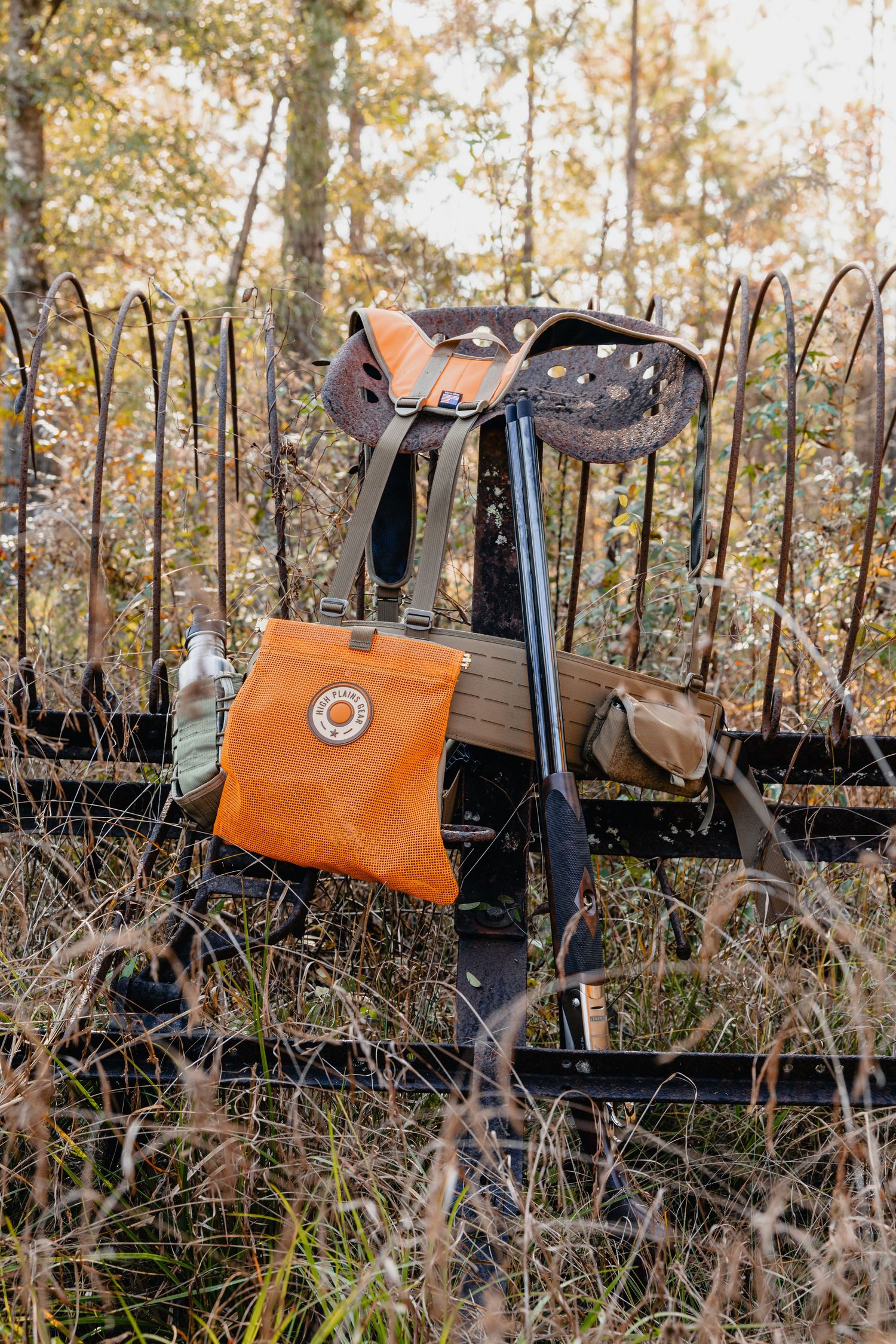Orange Fjallraven tote bag hanging on rustic equipment in an autumn forest setting.