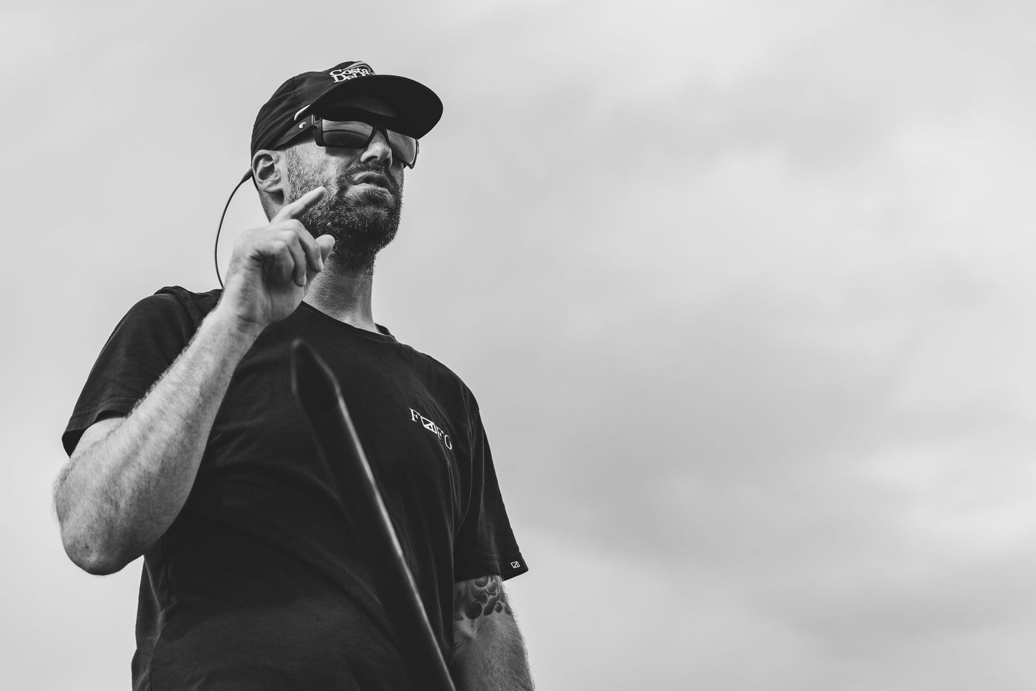 Silhouette of angler against cloudy sky in monochrome.