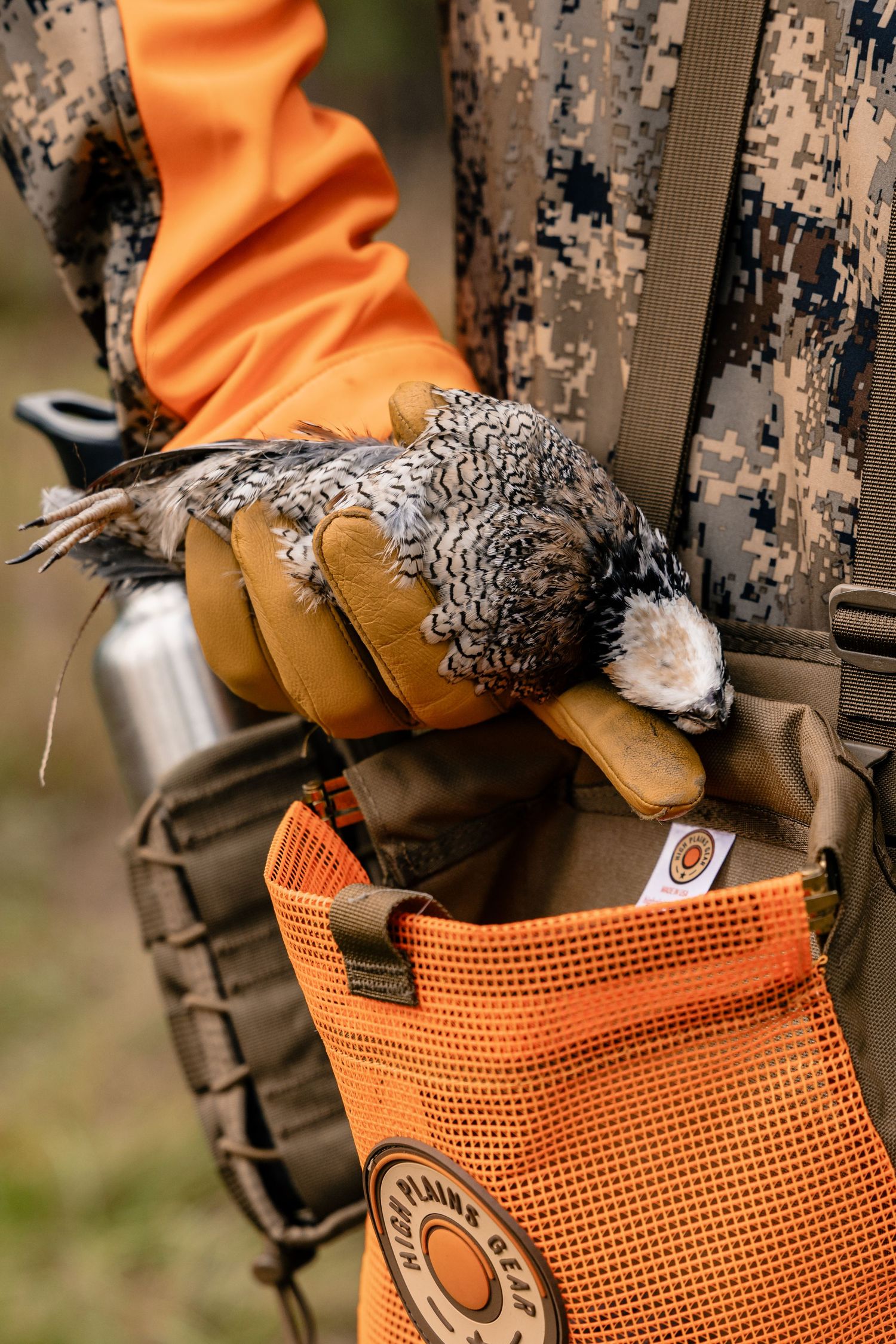 Close-up of hunting gear and equipment attached to orange tactical vest.