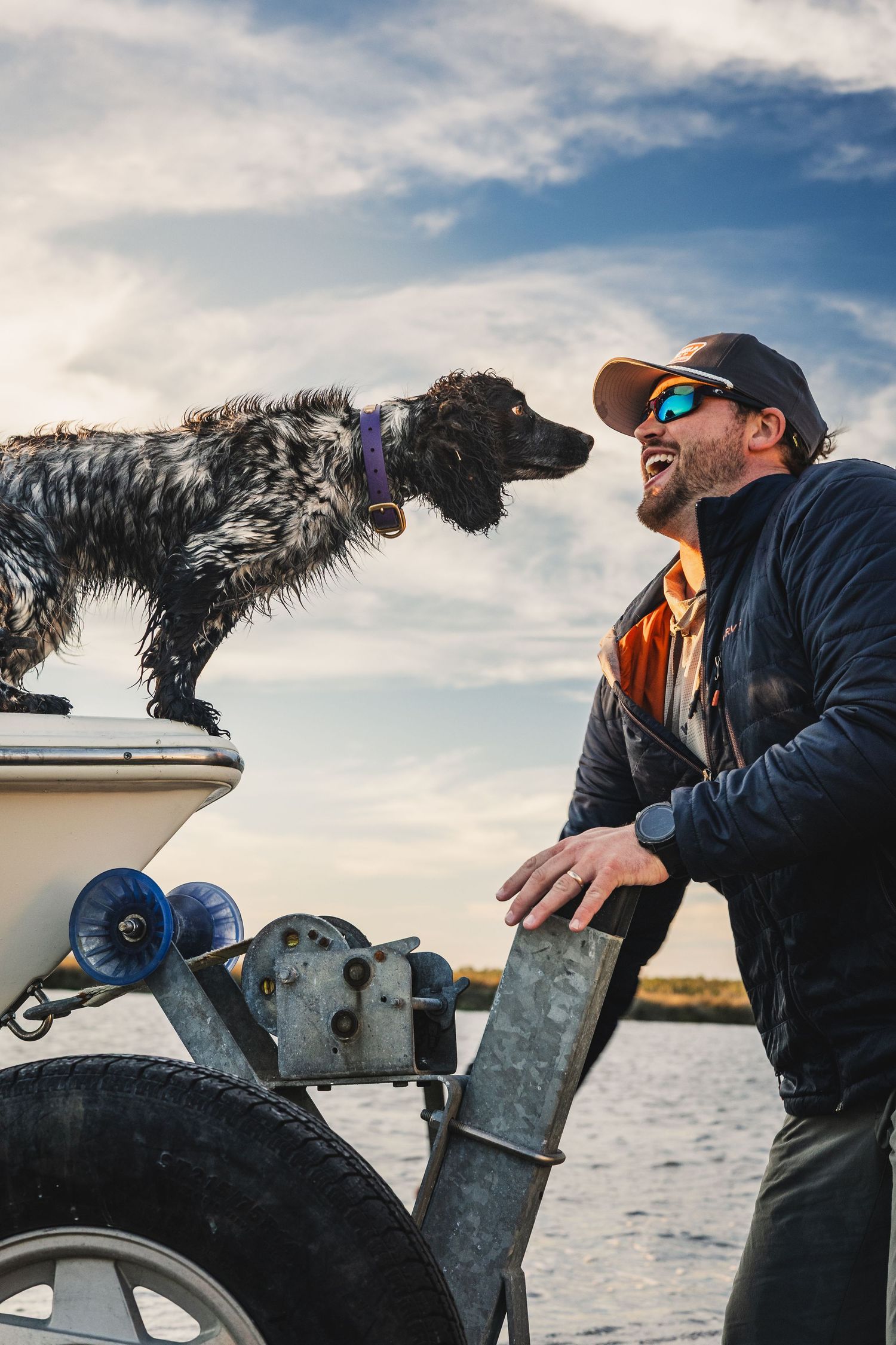 Fishing companions and their dog enjoying a day on the water with scenic cloudy skies.