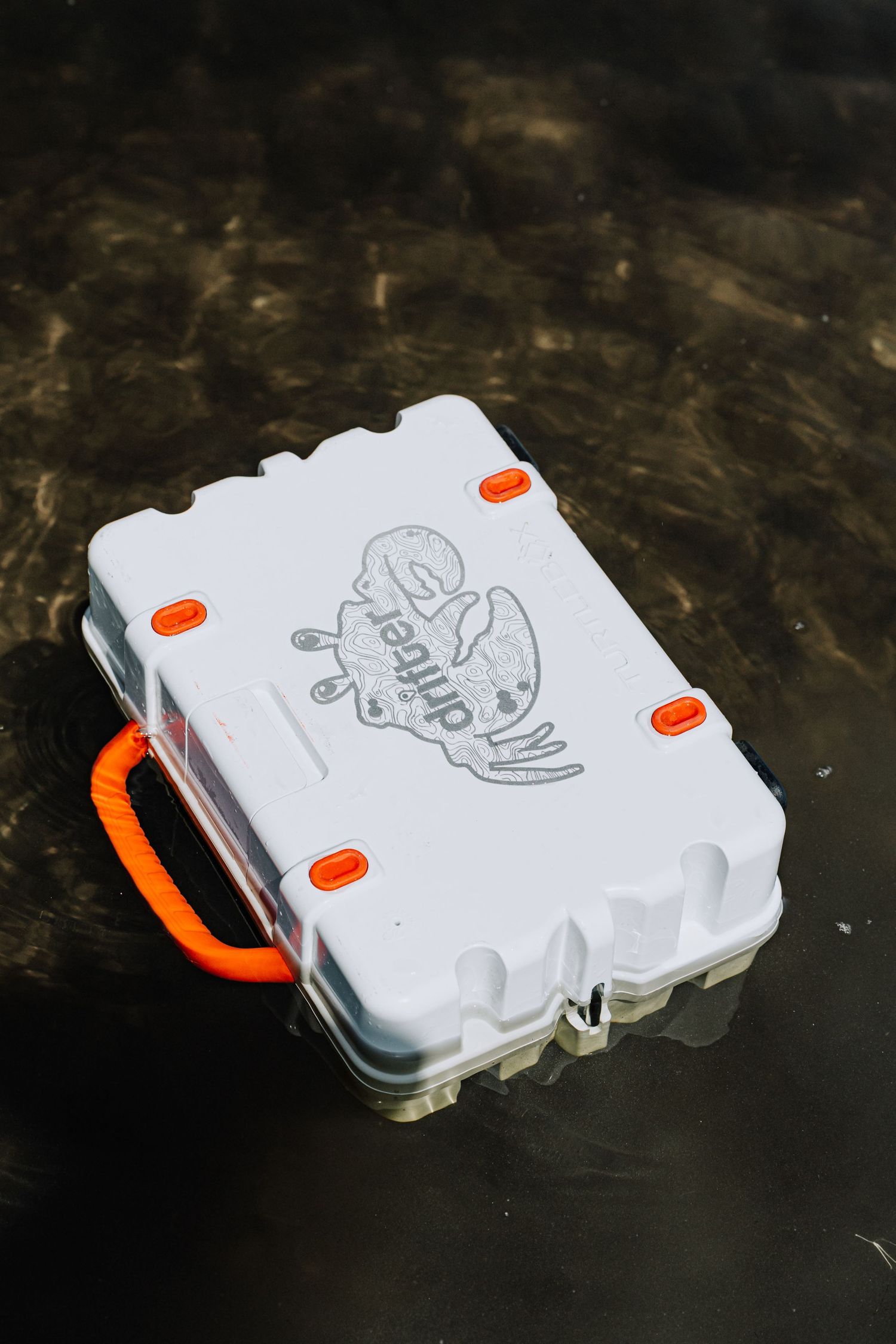 White waterproof case with orange handles and logo floating in dark water.