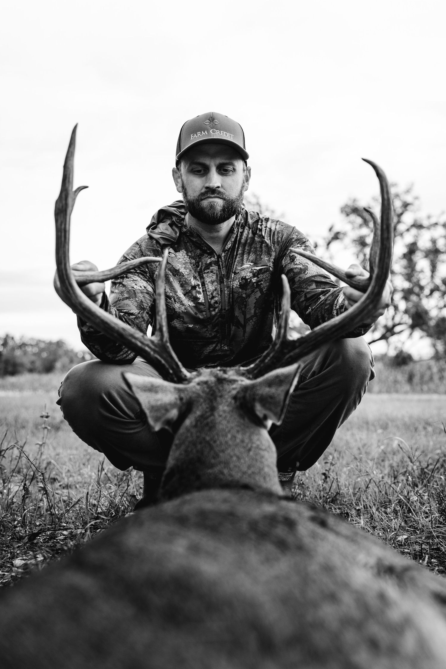 Black and white photo series showing a hunter posing with harvested deer antlers in a grassy field.