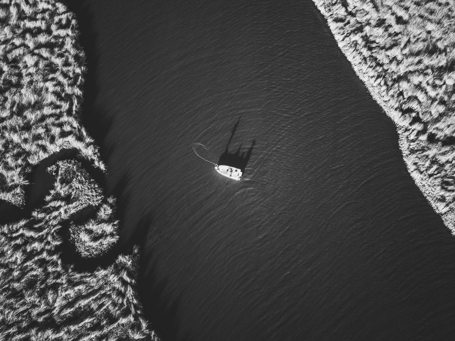 Aerial view of boats navigating through dark coastal waters.