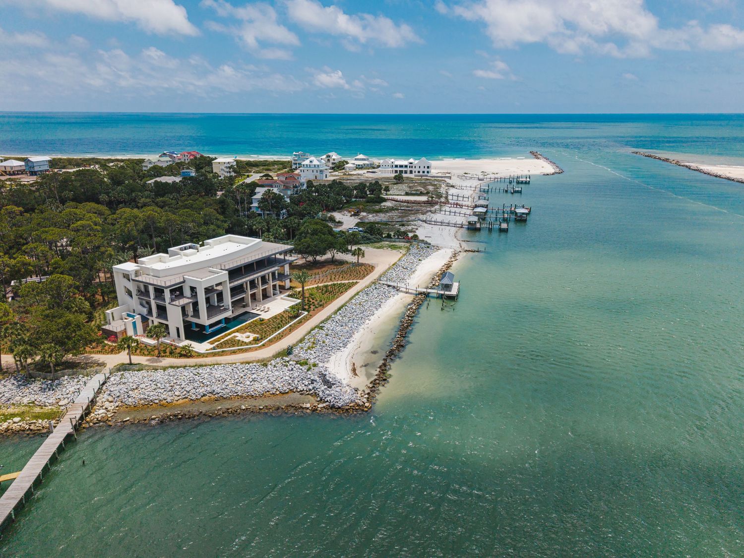 Aerial view of a coastal property with white buildings, docks, and crystal clear turquoise waters.