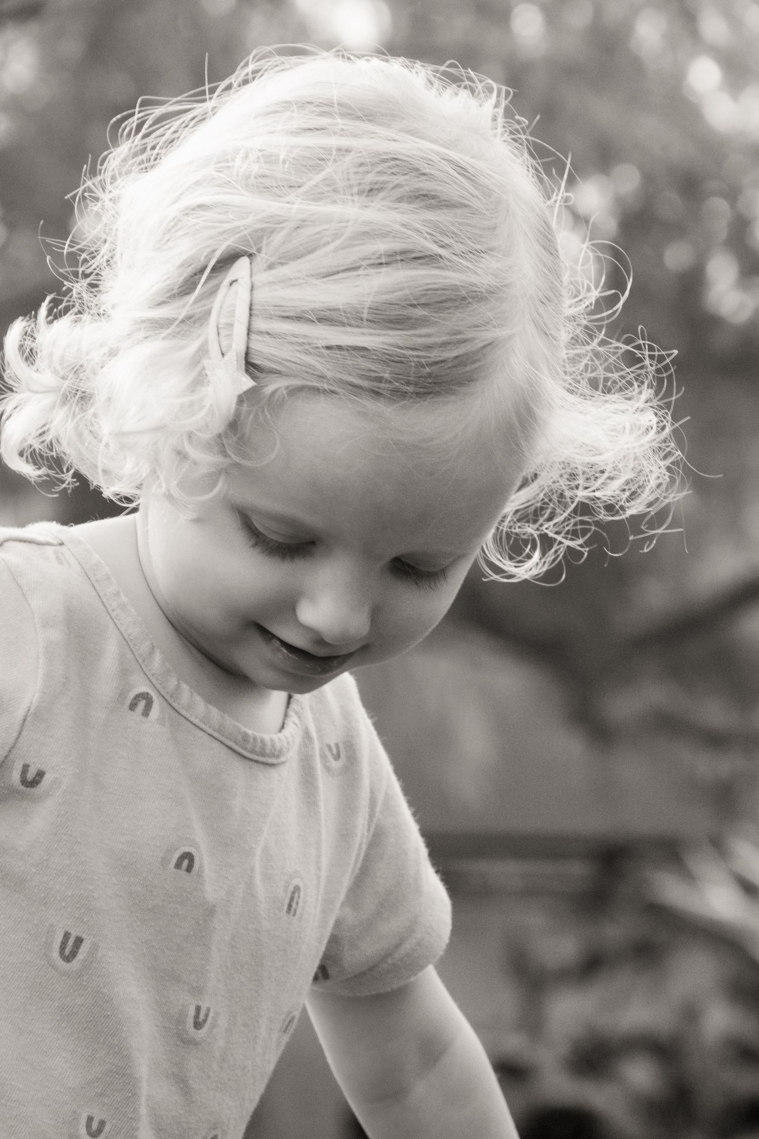 Black and white portrait of small child with wispy blonde hair gazing downward.