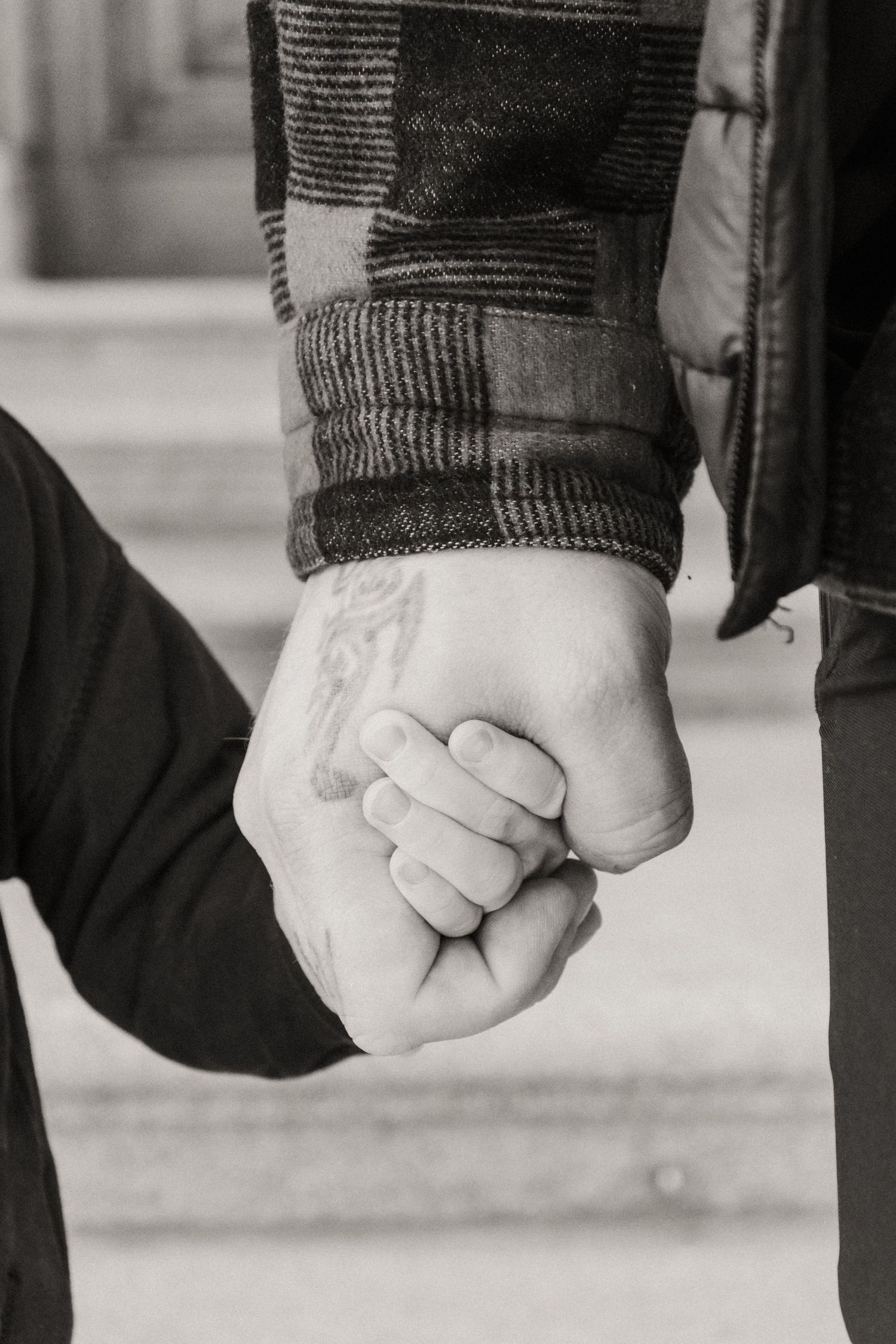 A black and white photo series showing two people holding hands, focusing on their intertwined fingers.