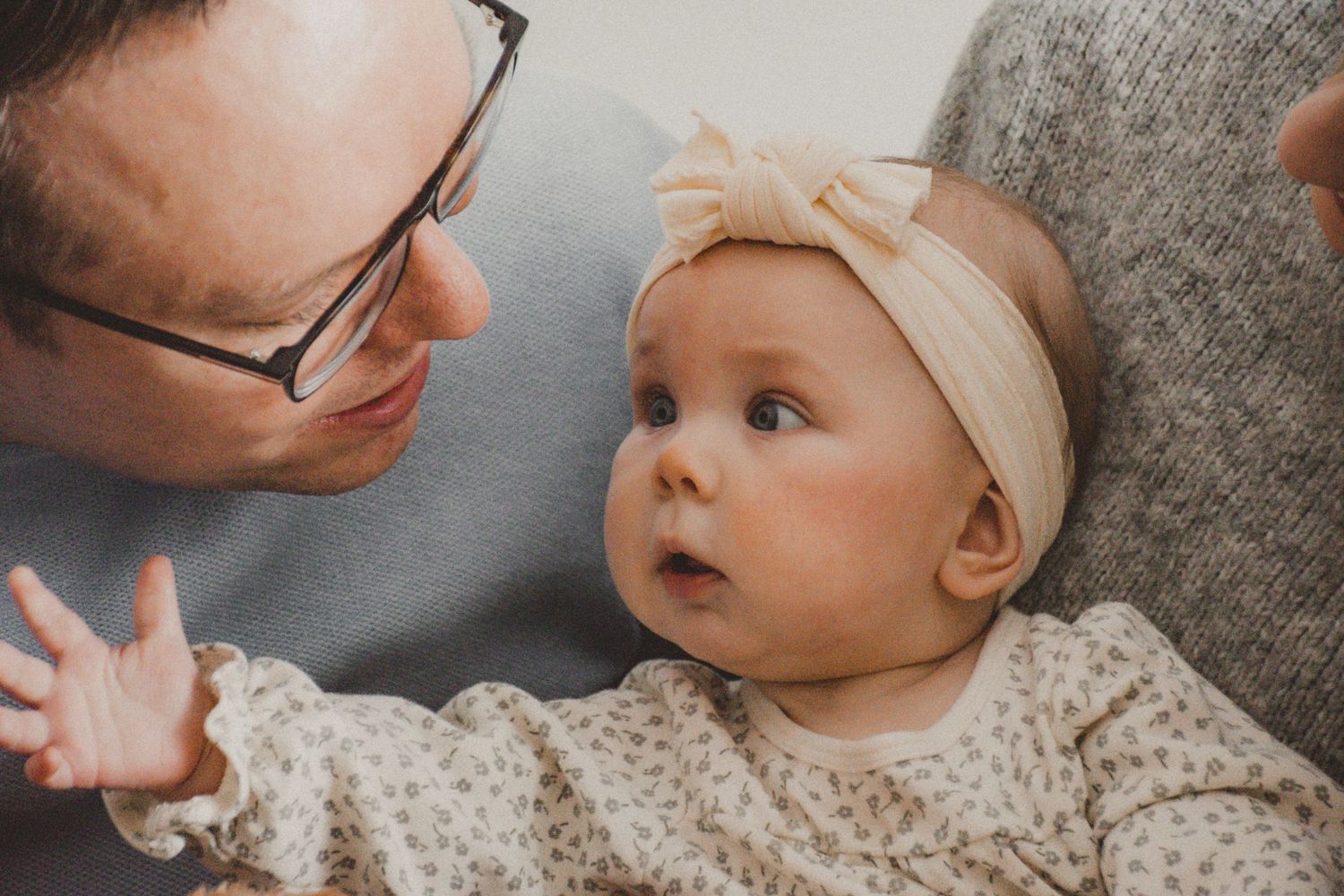 Close-up tender moment with baby in cream bow headband.