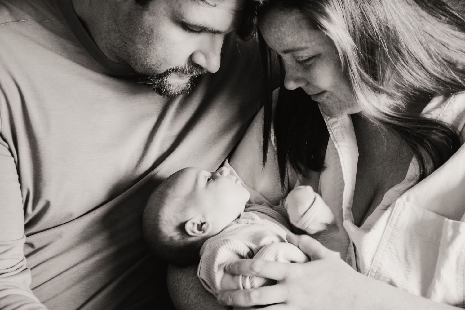 A tender black and white moment of parents bonding with their newborn baby.
