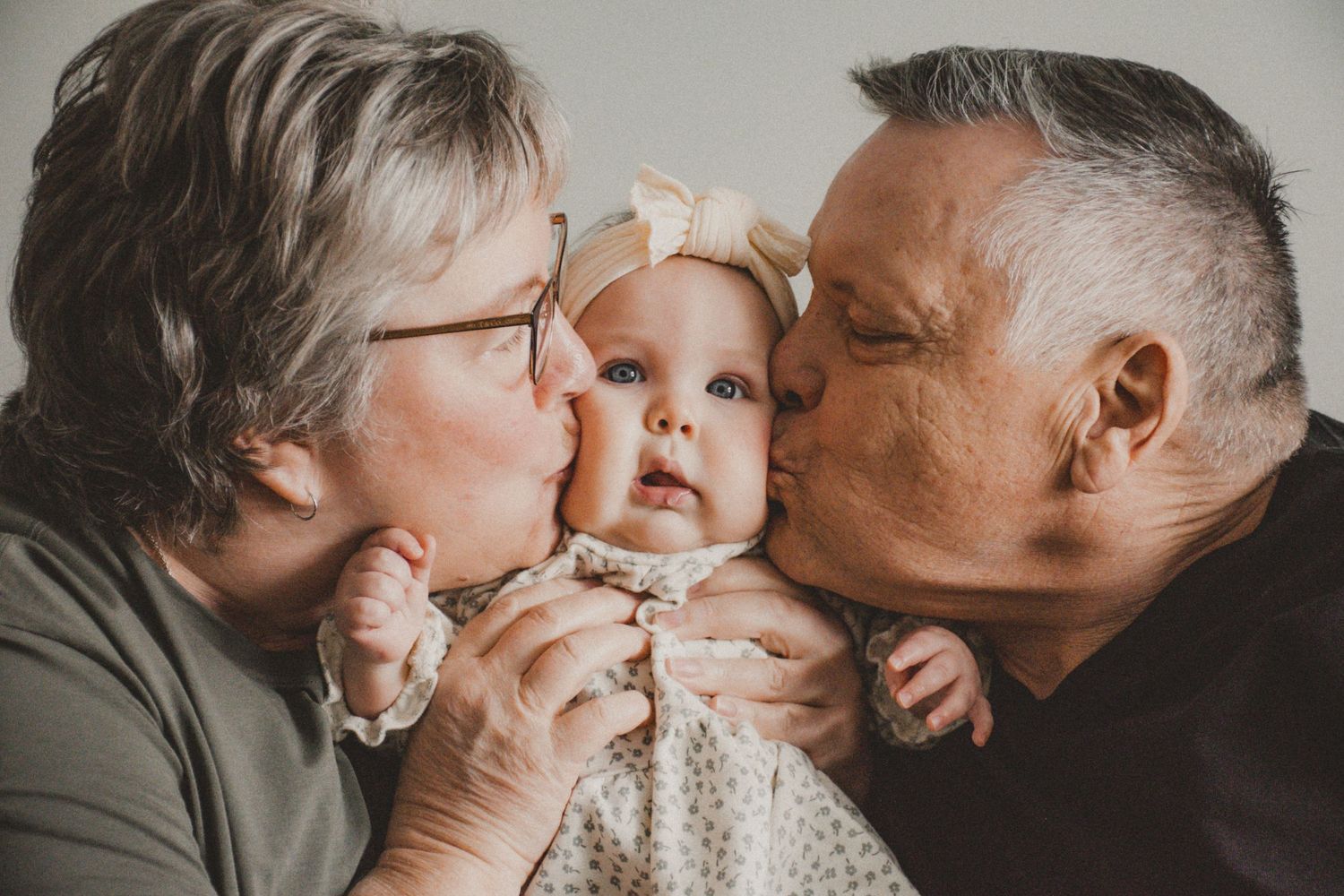 A tender moment captured with grandparents kissing their baby grandchild.