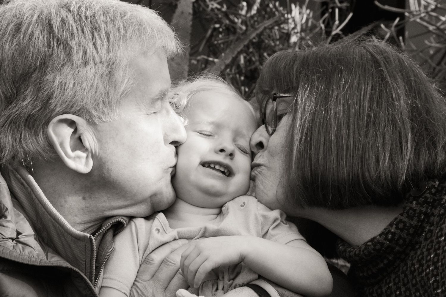 A black and white close-up of three generations sharing an affectionate moment.