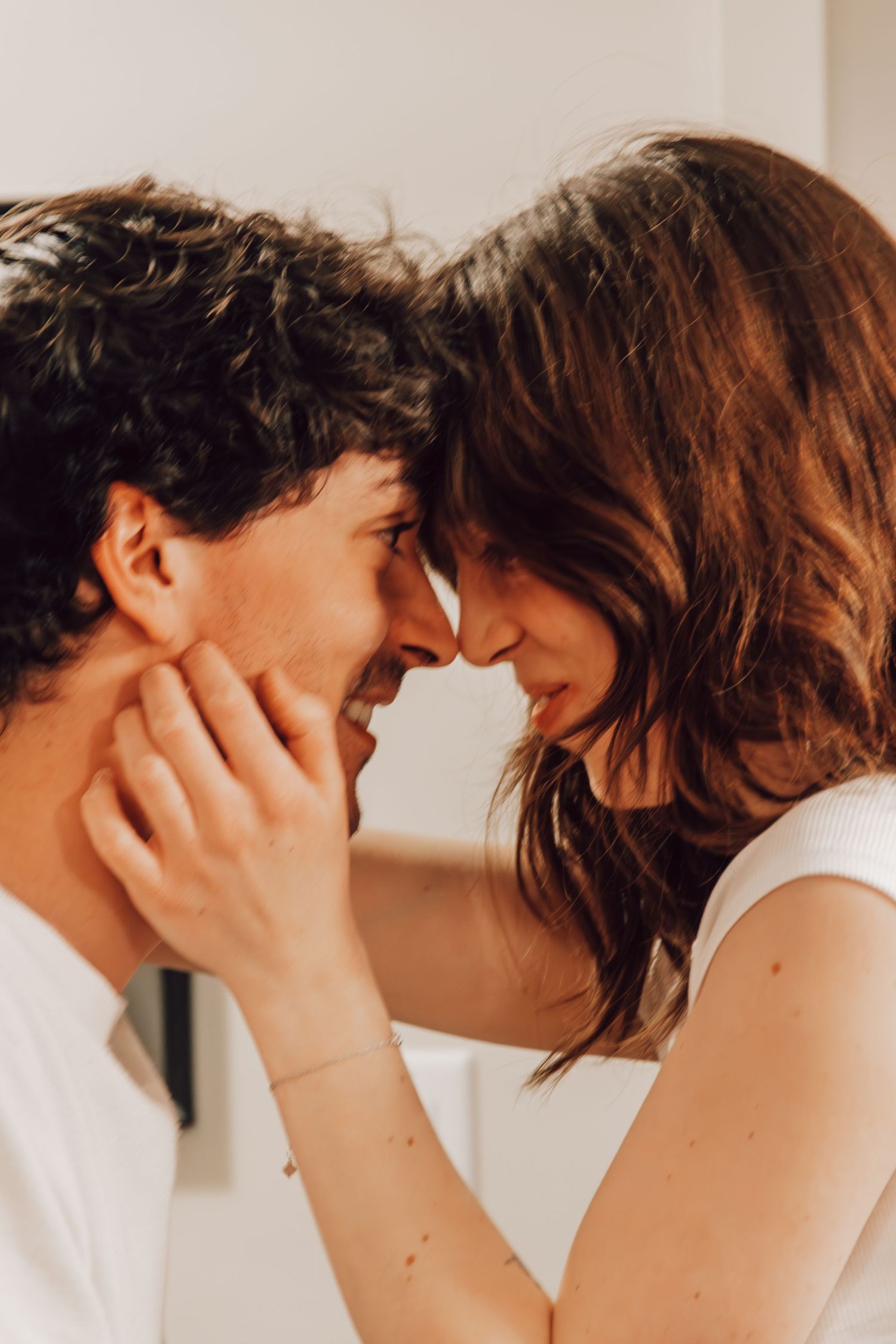 Close up of a tender romantic moment between two people in white clothing.