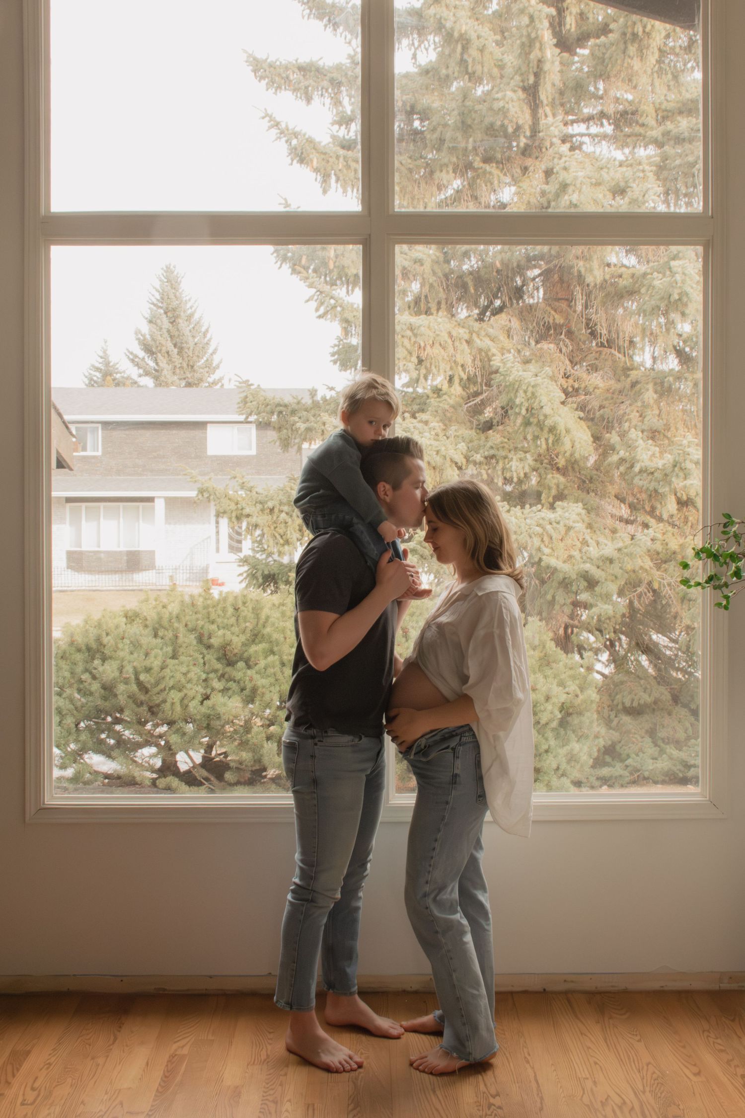 A family shares a tender moment together by a sunlit window in their home, creating a warm and intimate atmosphere.
