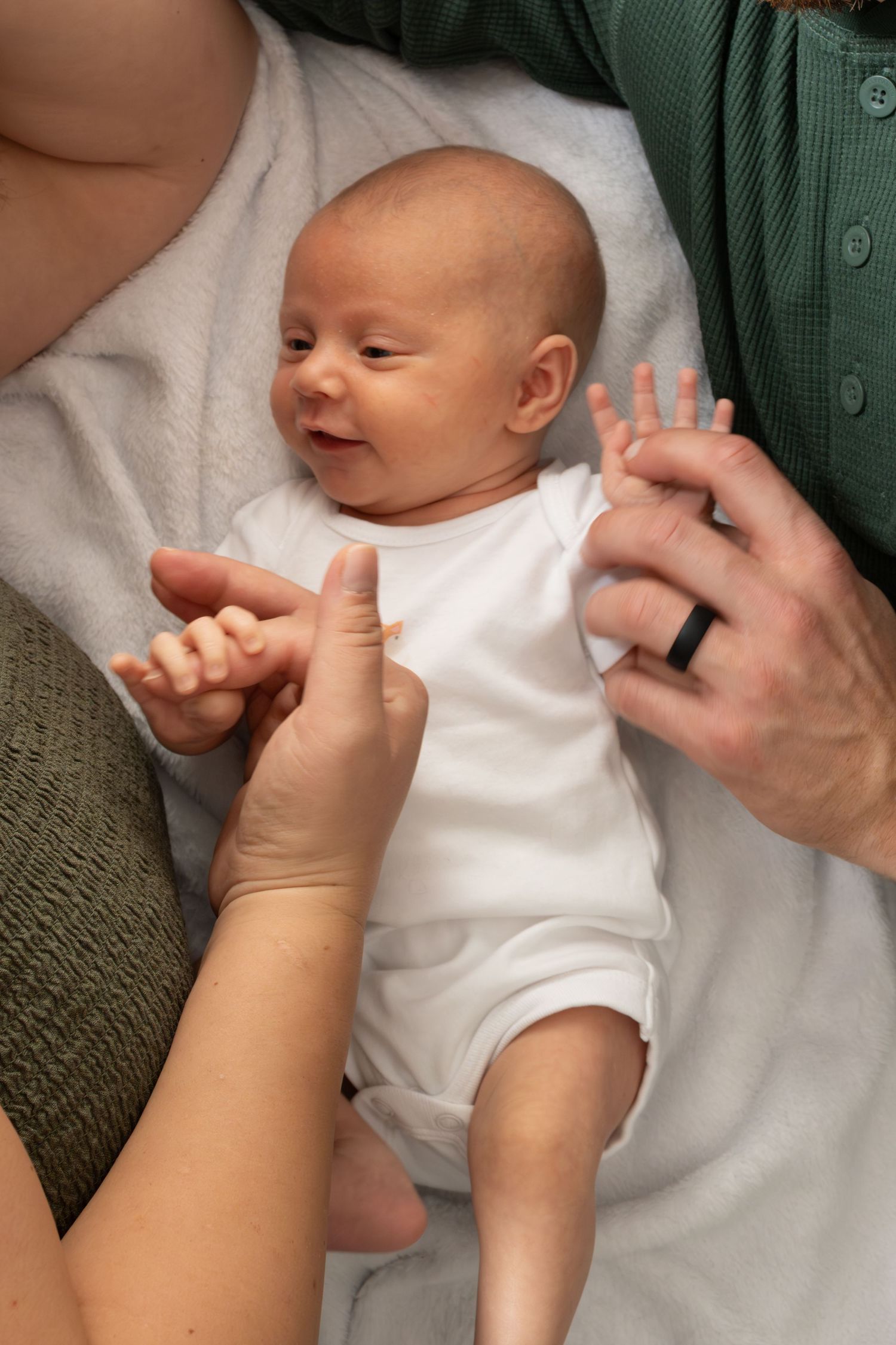 A sequence of photos showing a baby's hand being gently massaged by an adult hand against a green background.