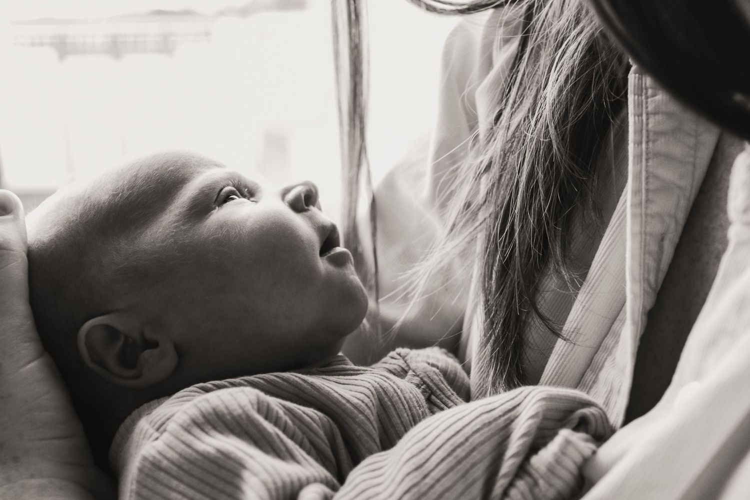 Close-up black and white portrait of infant looking upward.
