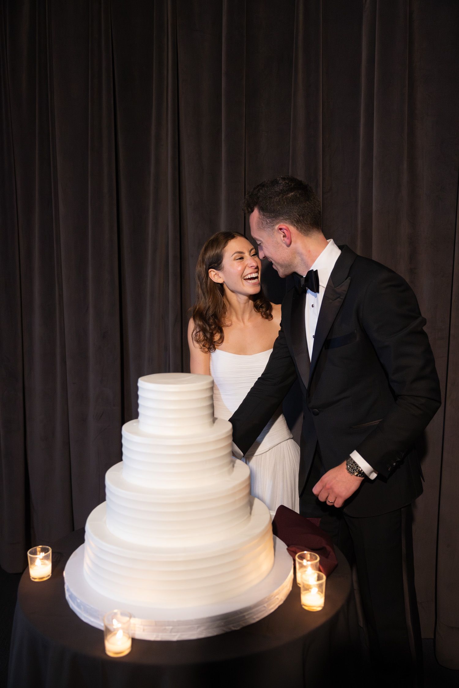 Couple laughing and cutting their wedding cake in NYC