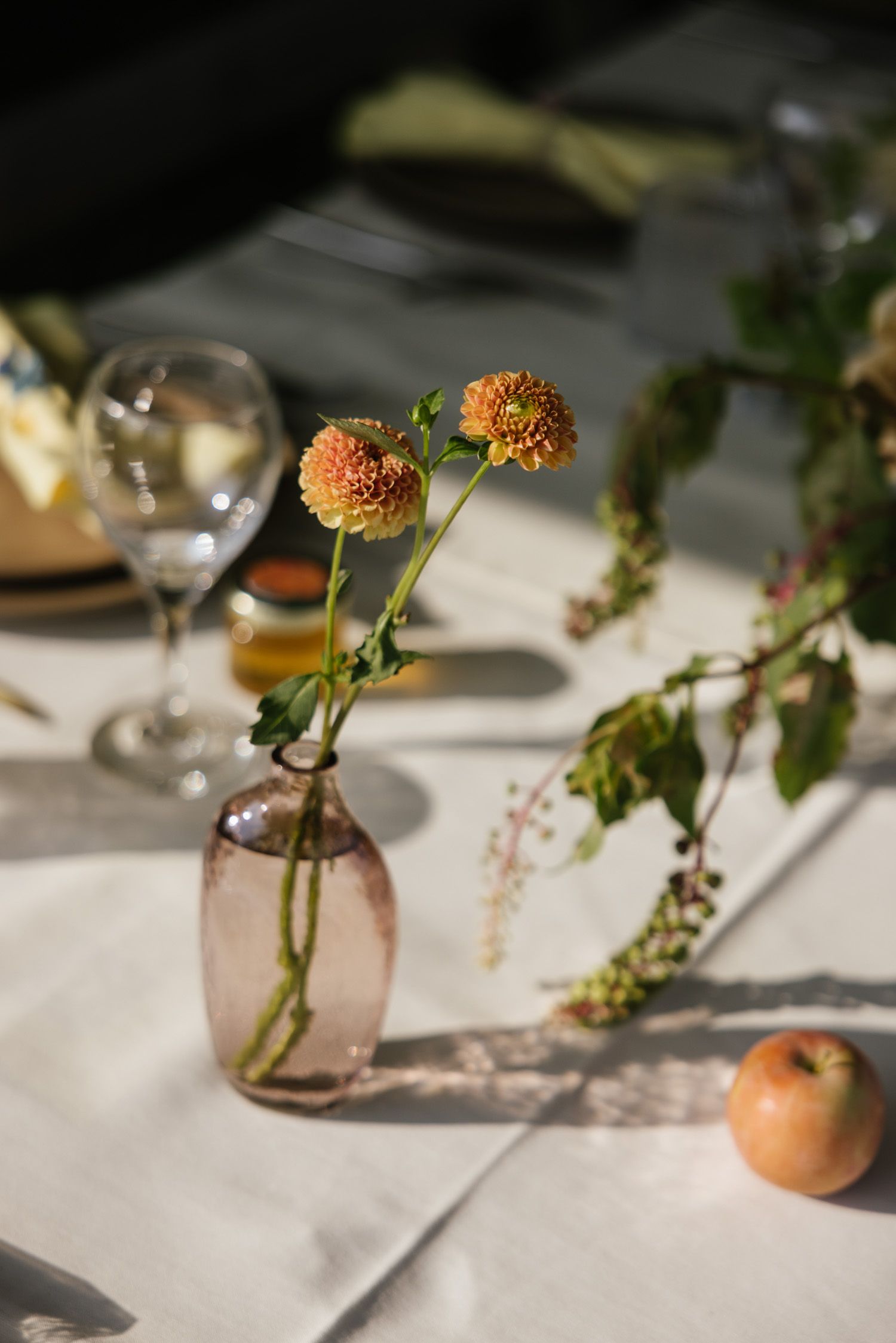 Orange dahlia flowers with an apple on the reception table at a Rose Hill Farm wedding.