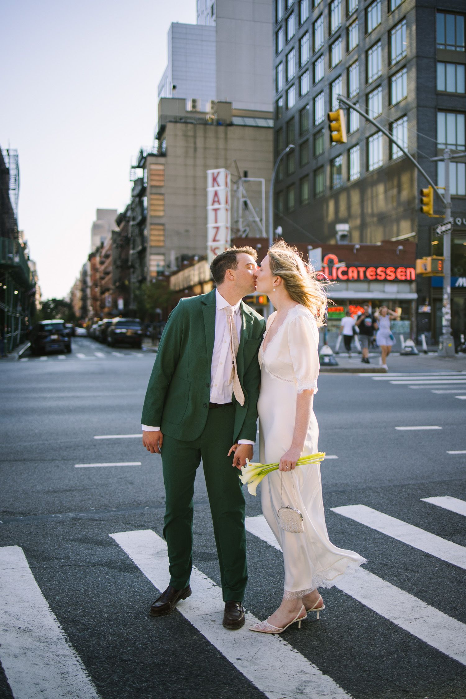 Bride and groom kissing as they cross the street in New York City near Katz's Delicatessen