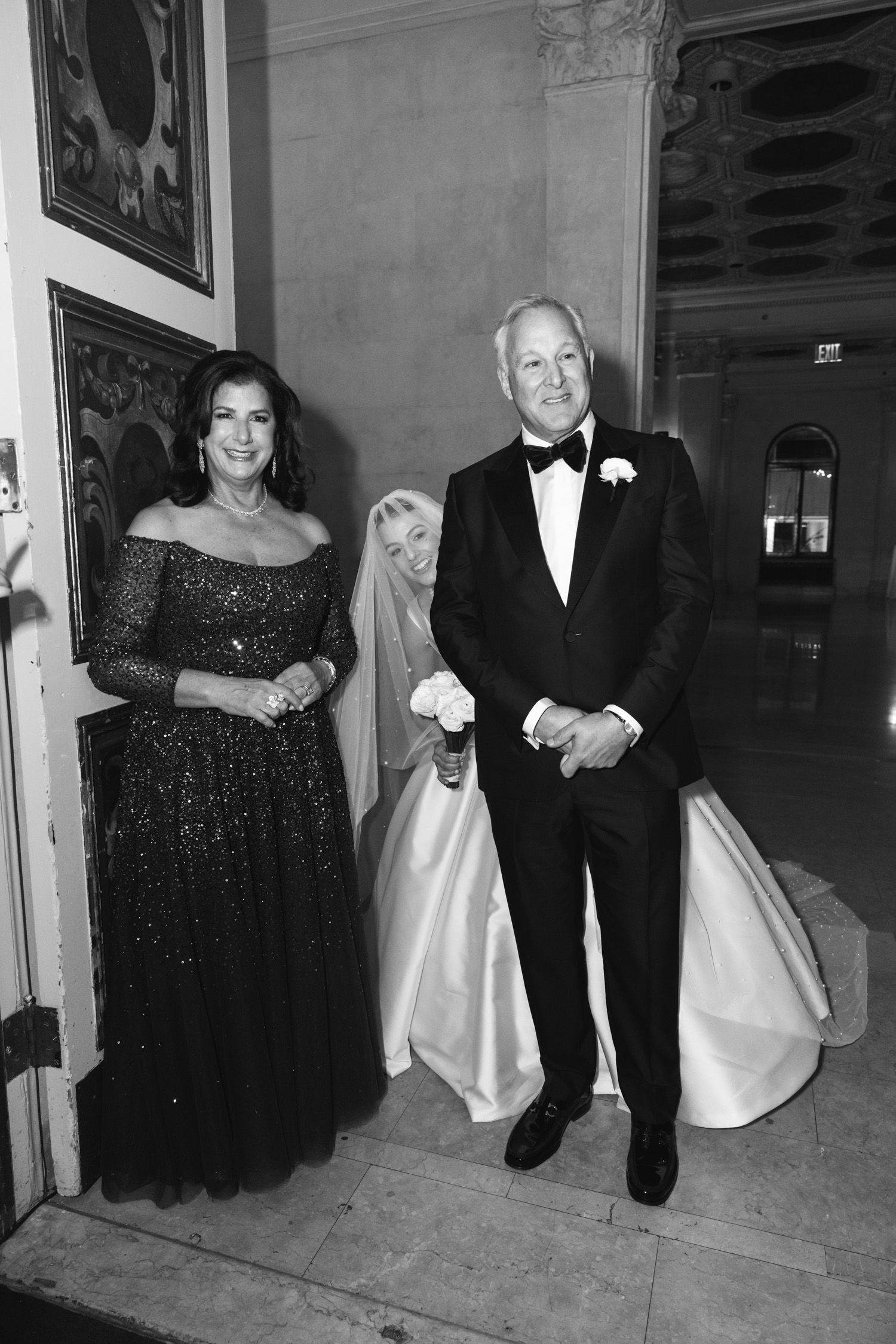 Bride peaking over her parents shoulders before she walks down the aisle at The Plaza in NYC
