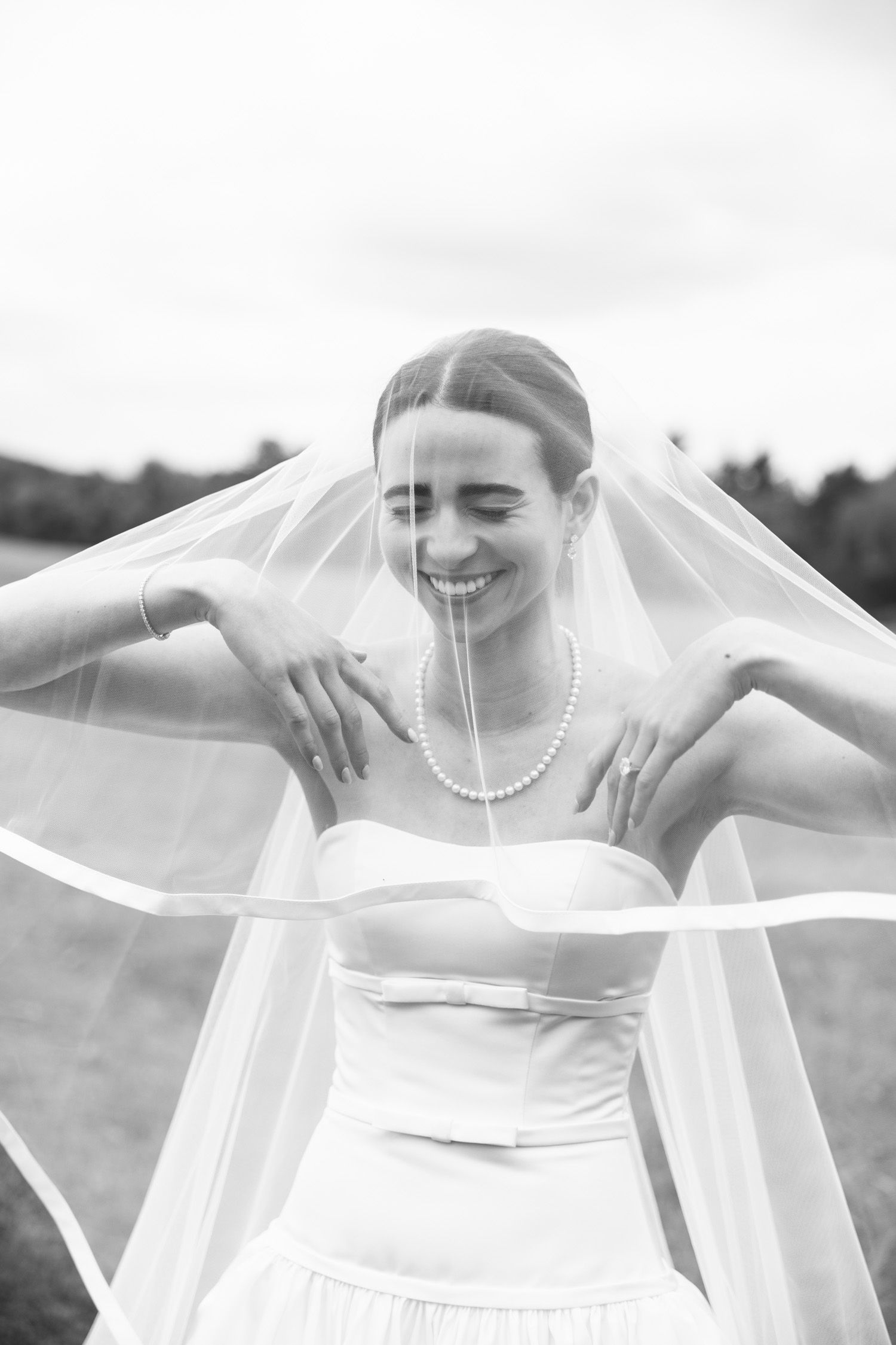 Black and white portrait of a bride lifting her veil at LionRock Farm wedding