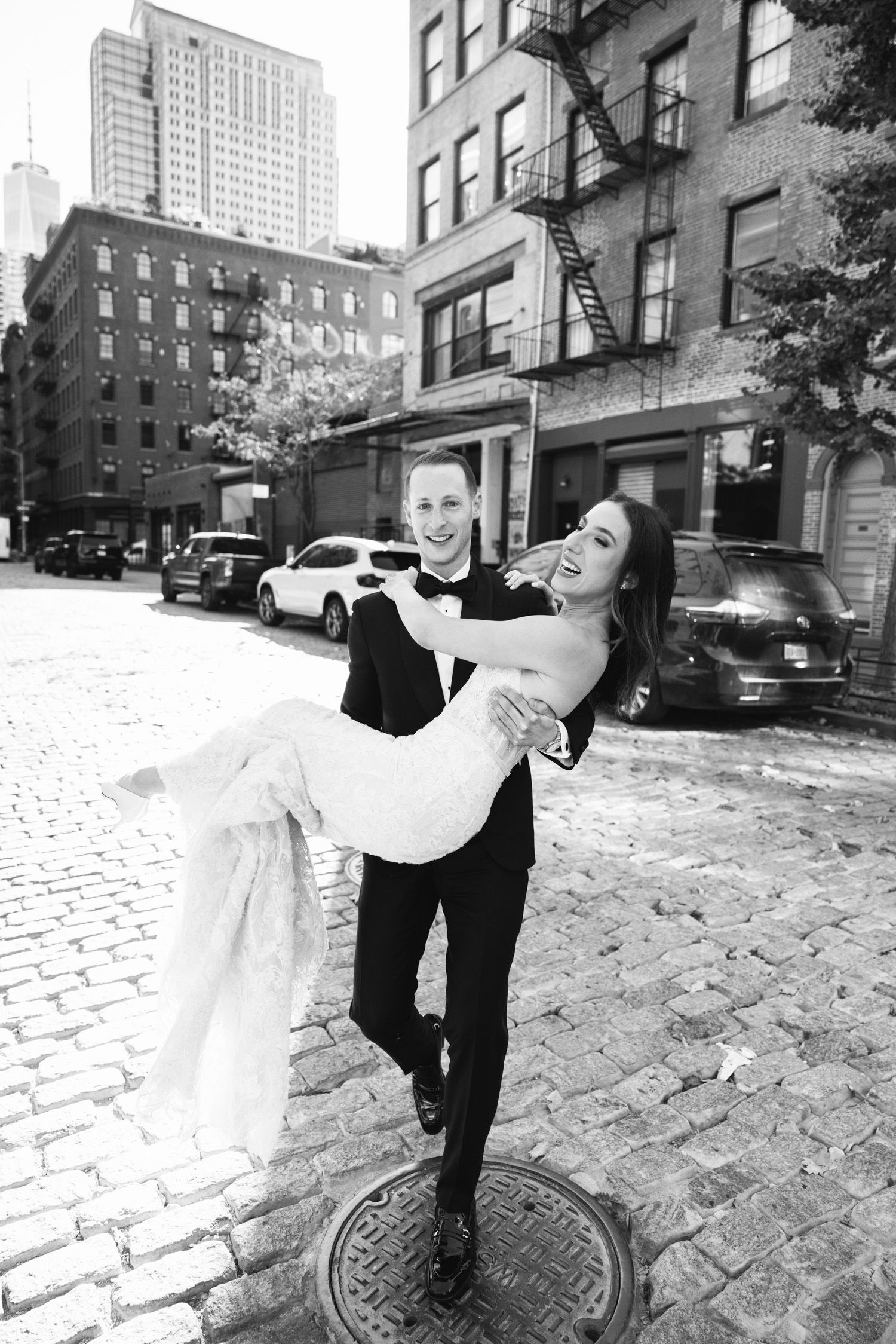 Groom lifting bride on cobblestone NYC street