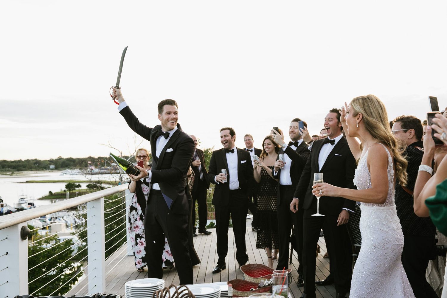 Groom opening champagne in front of guests at Peconic Bay Yacht Club in NY