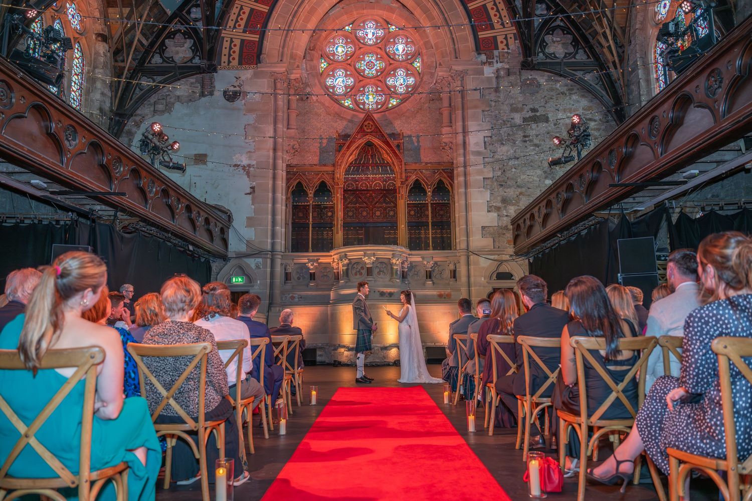 Guests seated in rows inside a historic church venue with stone walls and gothic architecture illuminated for an event.