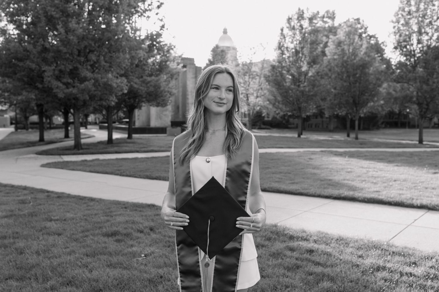 Black and white portrait of person standing on campus grounds.