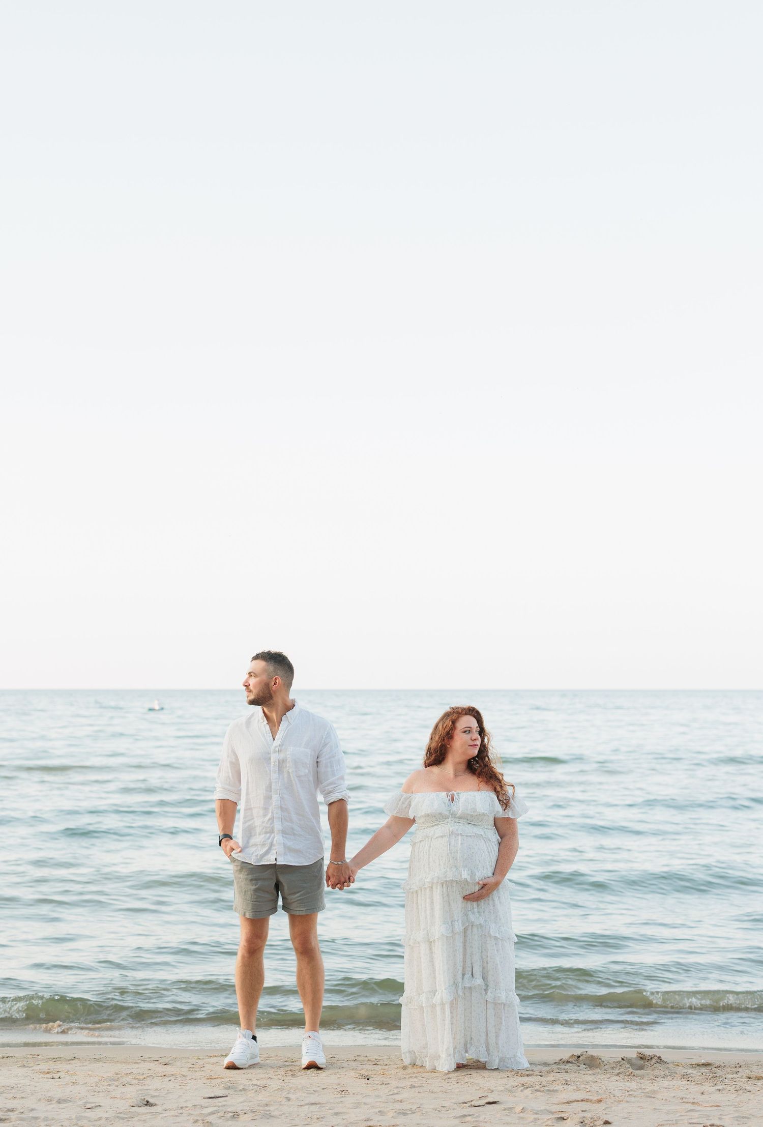 A couple stands together on a sandy beach at sunset holding hands by the ocean.

Rochester NY wedding photographer
