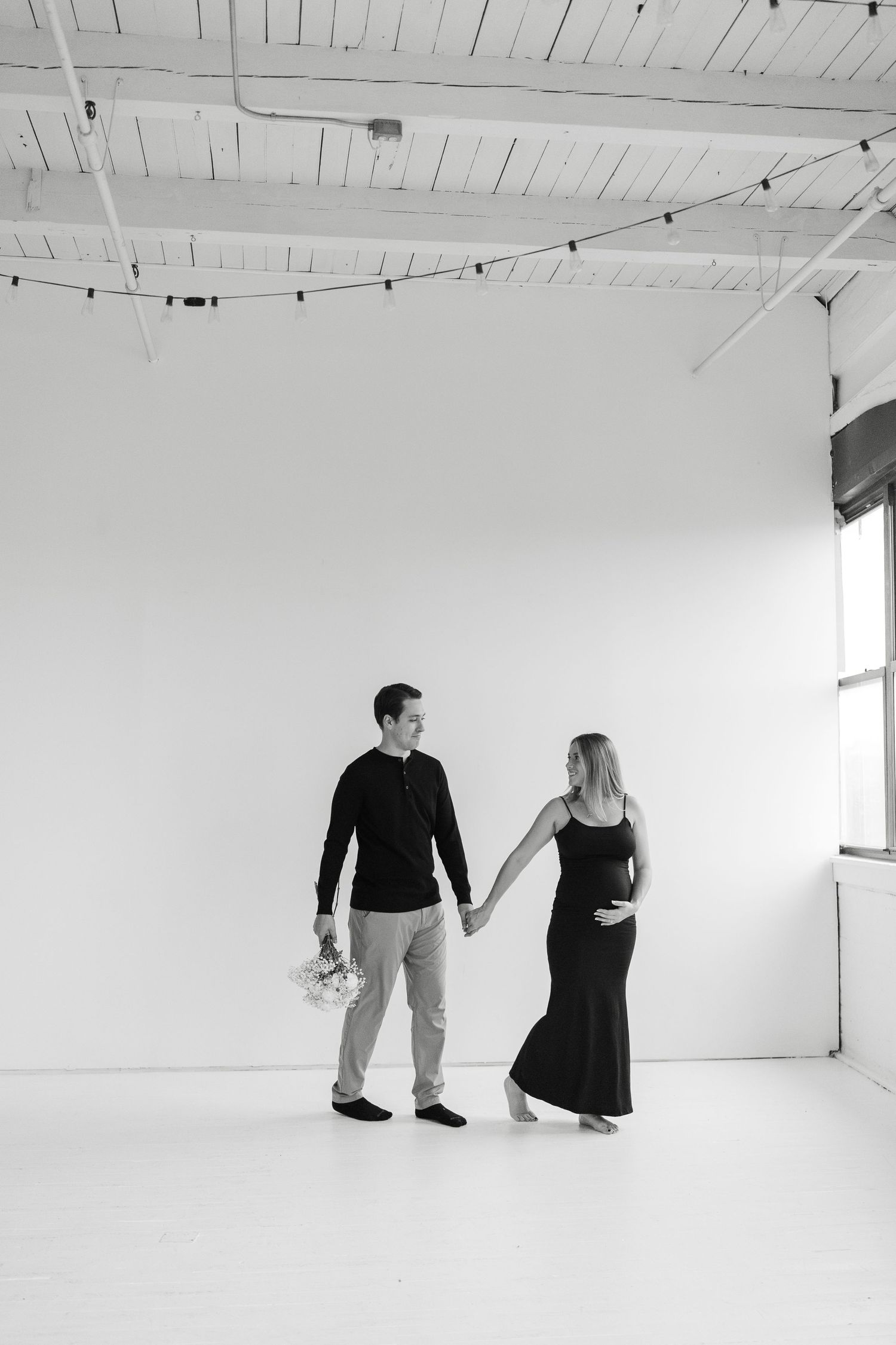 A minimalist black and white photo series showing two figures in a white studio space creating dynamic poses.