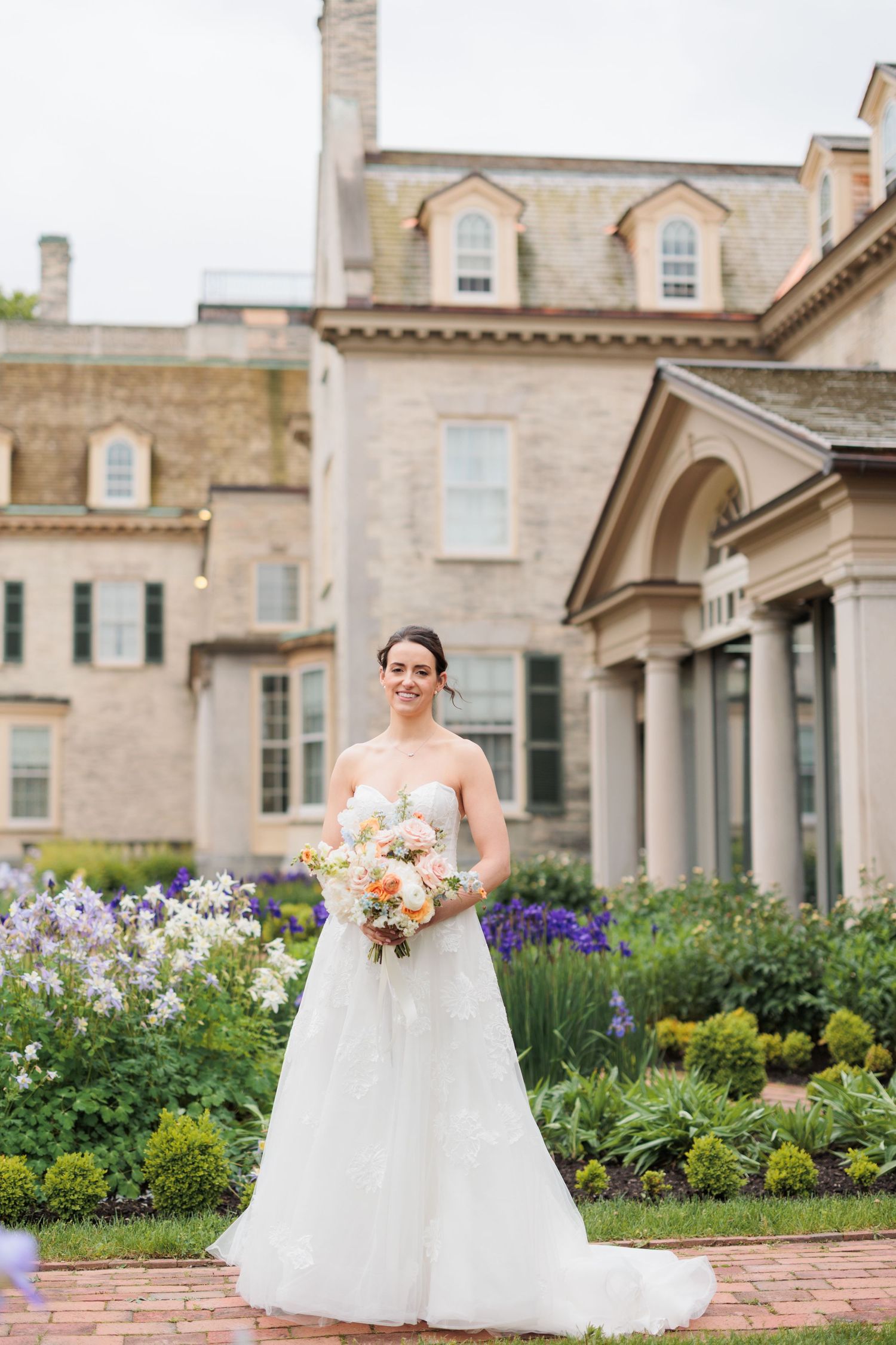 Elegant wedding portraits taken in front of historic mansion with manicured gardens.