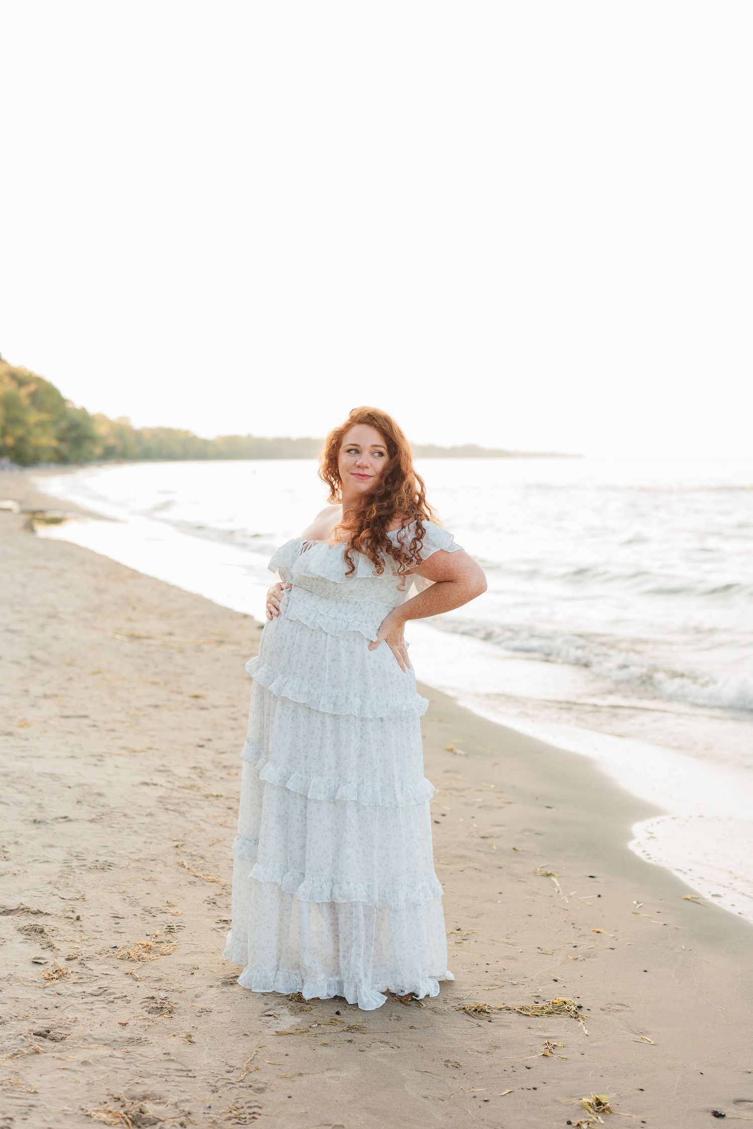 A woman in a flowing white lace dress poses on a beach at sunset.

Rochester NY wedding photographer