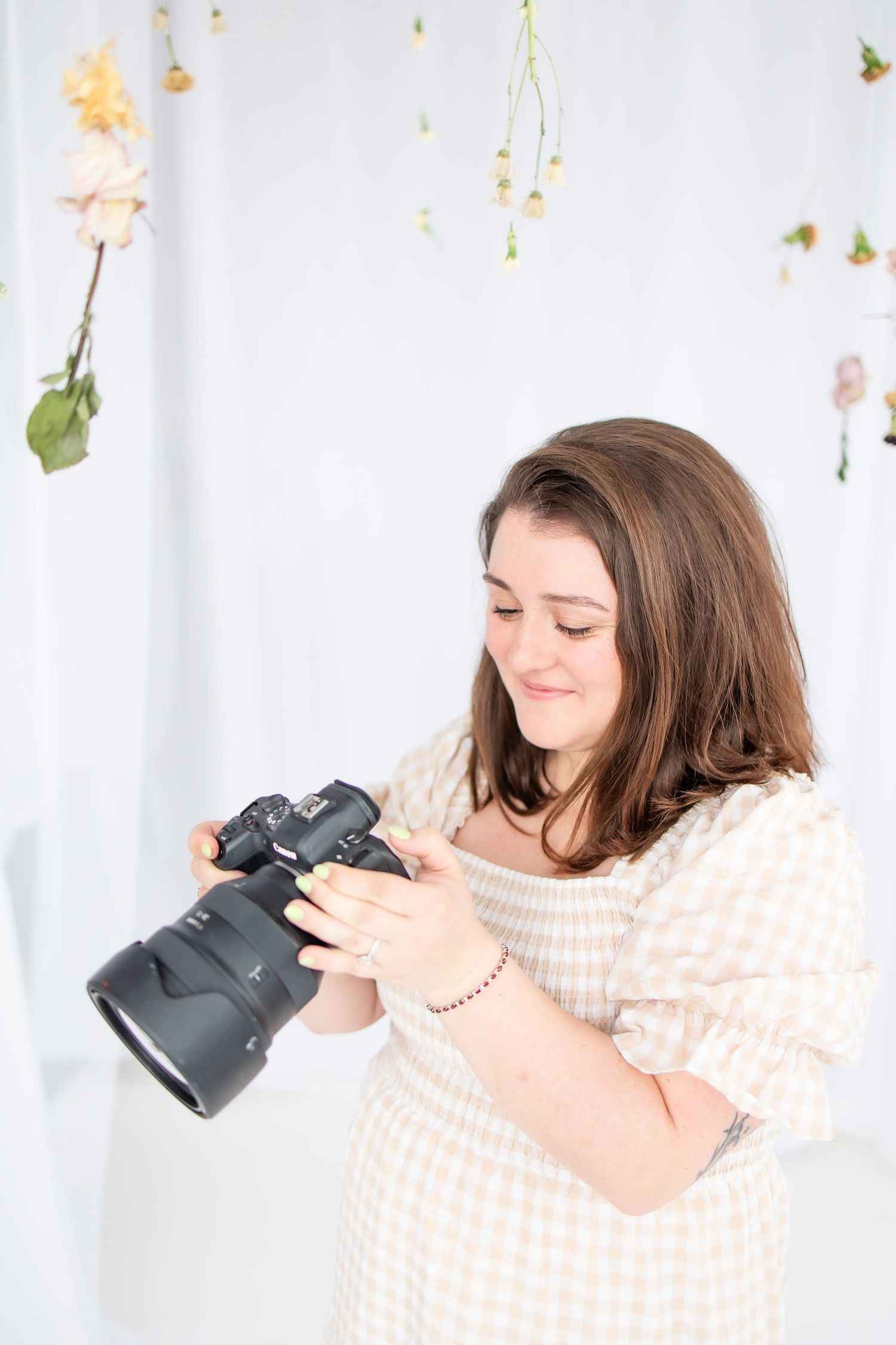 Photographer in checkered dress holding camera against white backdrop with falling leaves.

Rochester NY wedding photographer