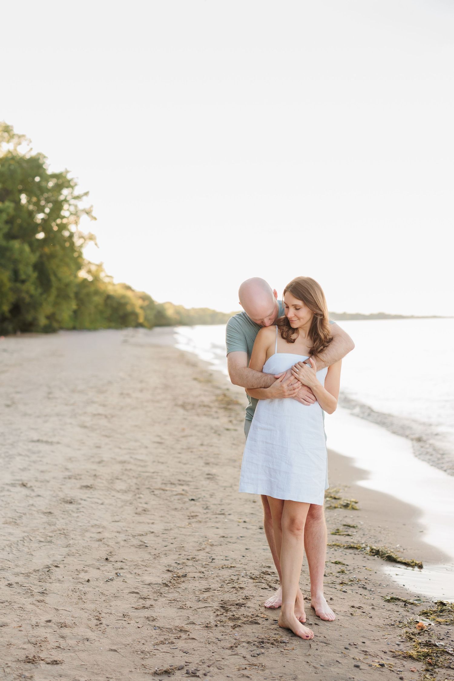 A romantic moment captured on a sandy beach at sunset with soft natural lighting.