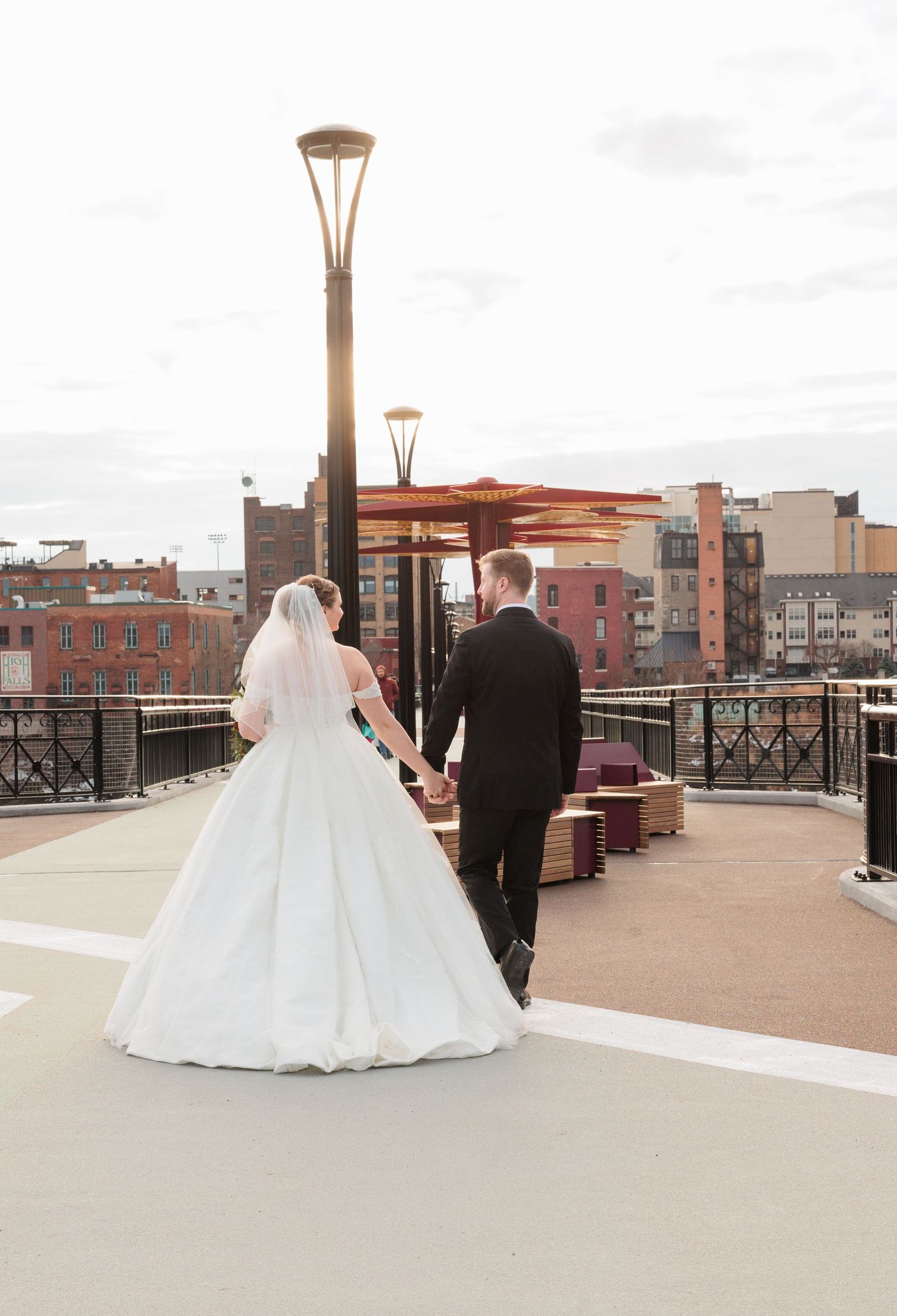 Wedding couple on rooftop terrace with urban cityscape backdrop.