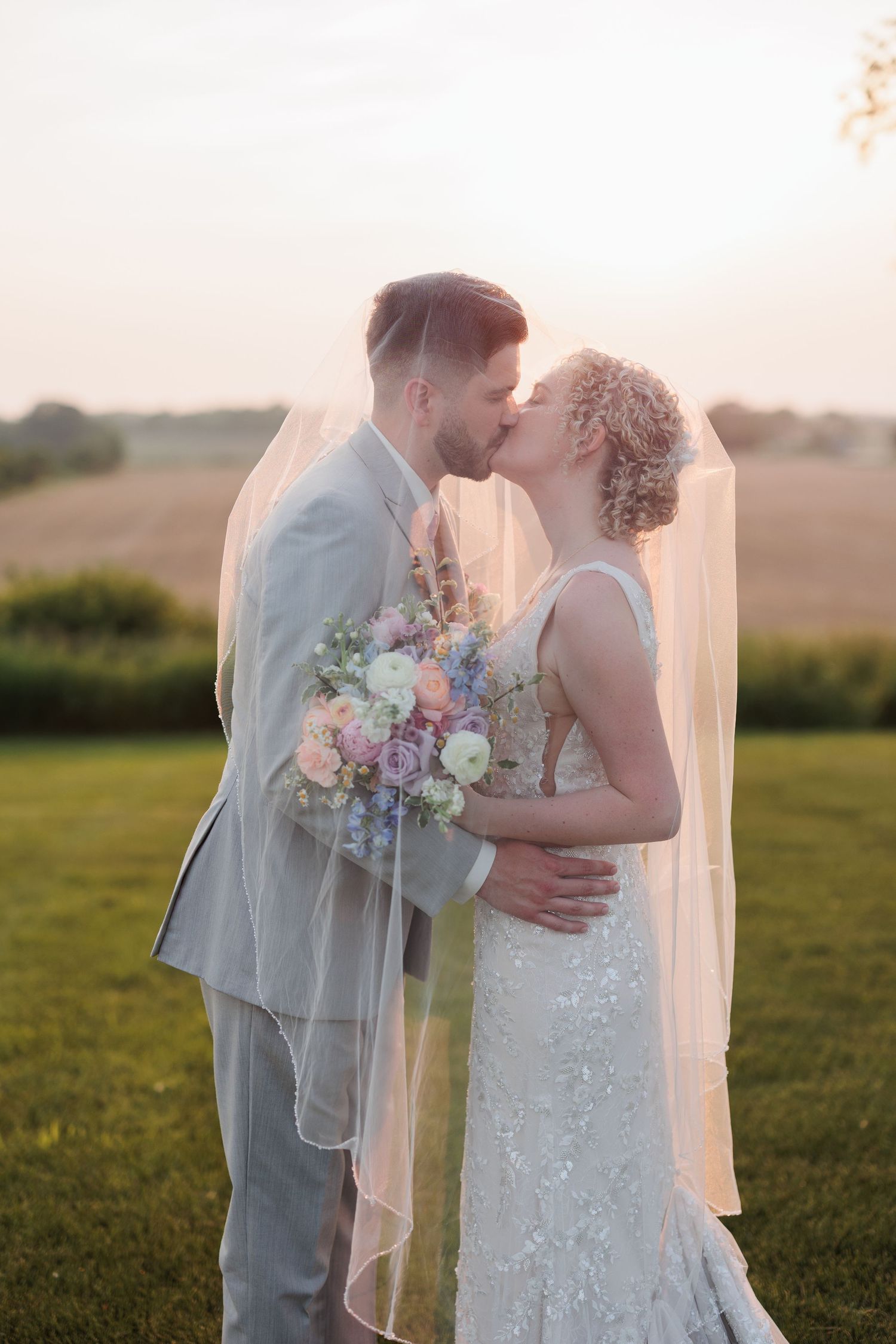 Romantic sunset wedding portraits in a field with soft golden light.