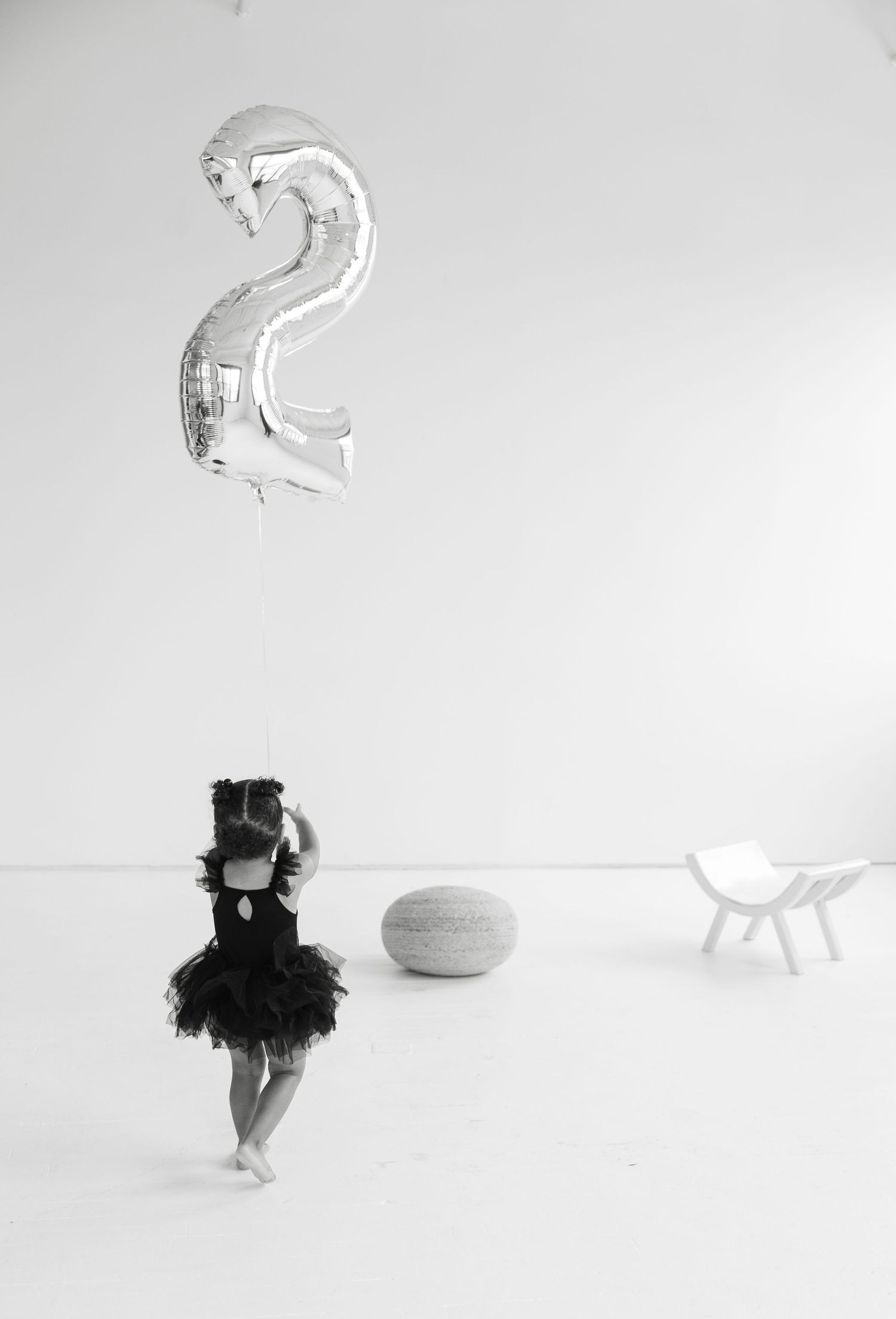 A silhouette of a child in a tutu dress stands beneath a silver number 2 balloon.

Rochester NY wedding photographer