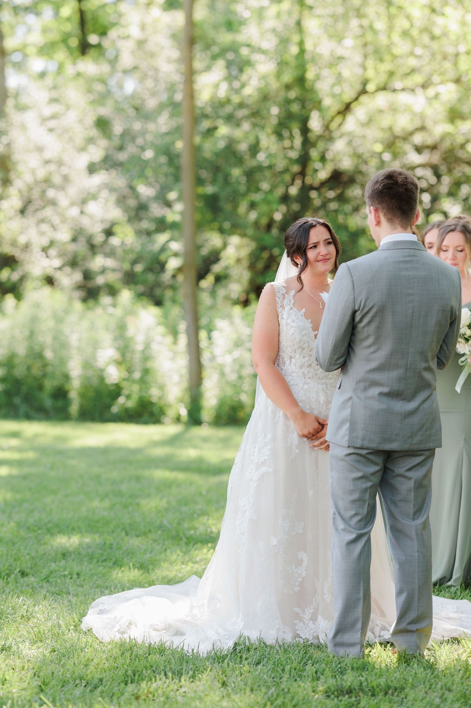 A wedding ceremony first look moment captured in a lush green outdoor setting.