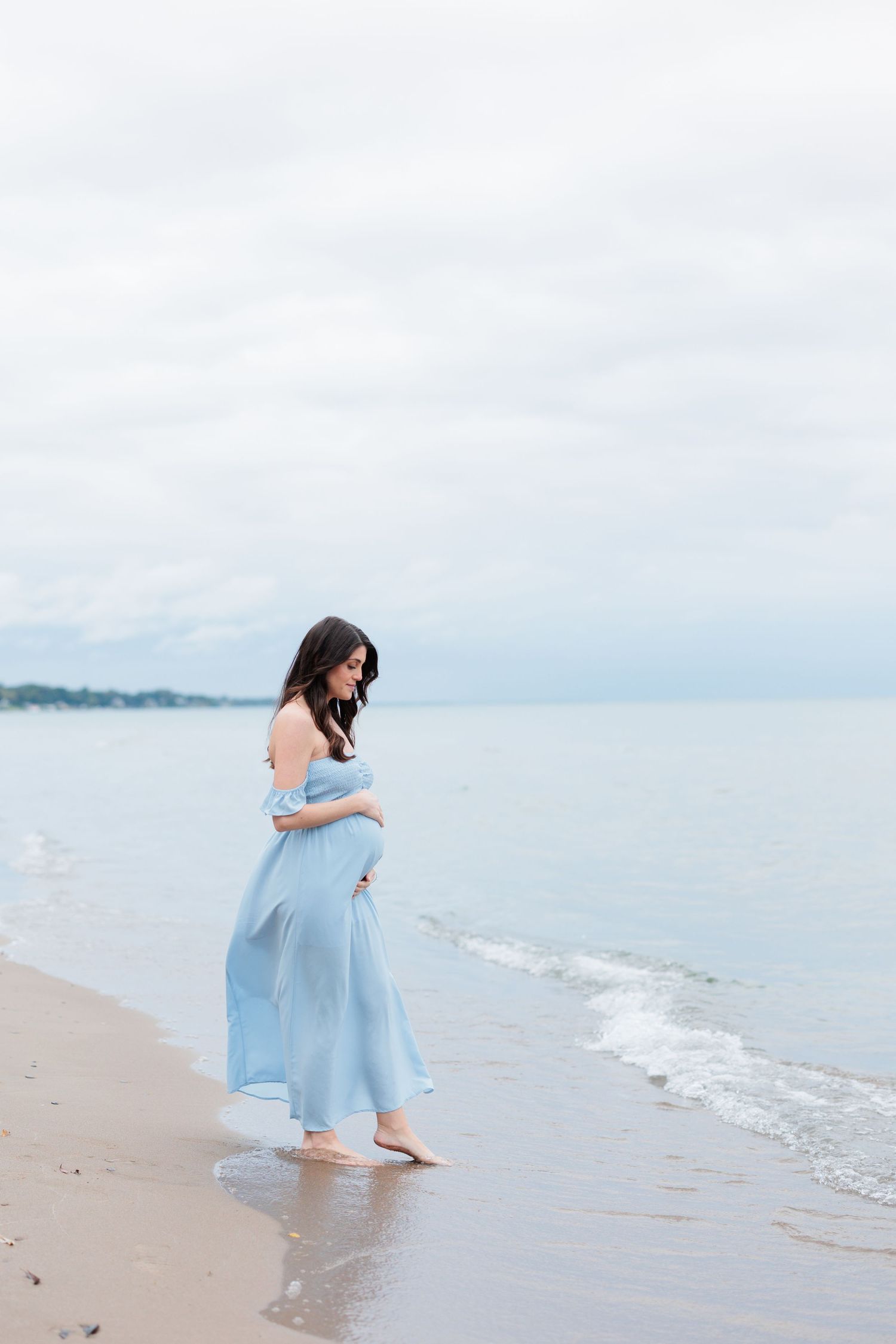 Woman in flowing blue dress stands at the ocean's edge during sunset.

Rochester NY wedding photographer
