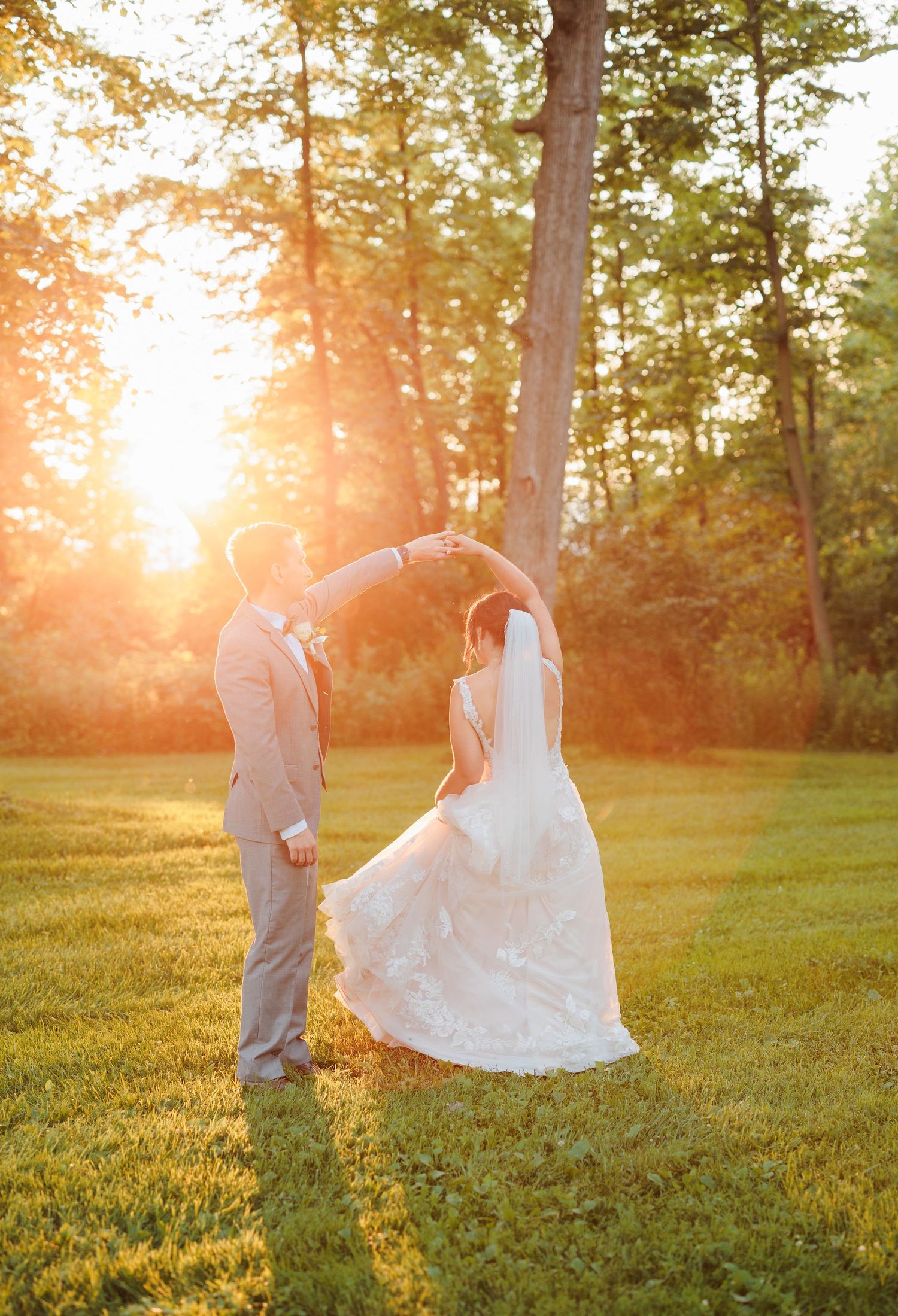 Golden hour wedding photos with couple dancing in grassy field.