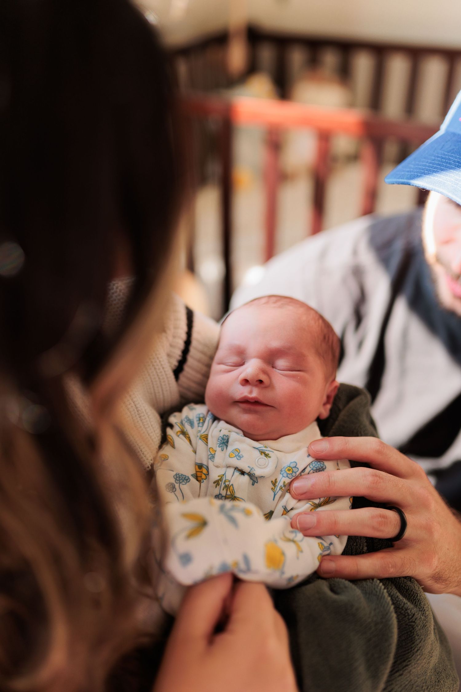A sleeping newborn in floral sleepwear being cradled gently.

Rochester NY wedding photographer