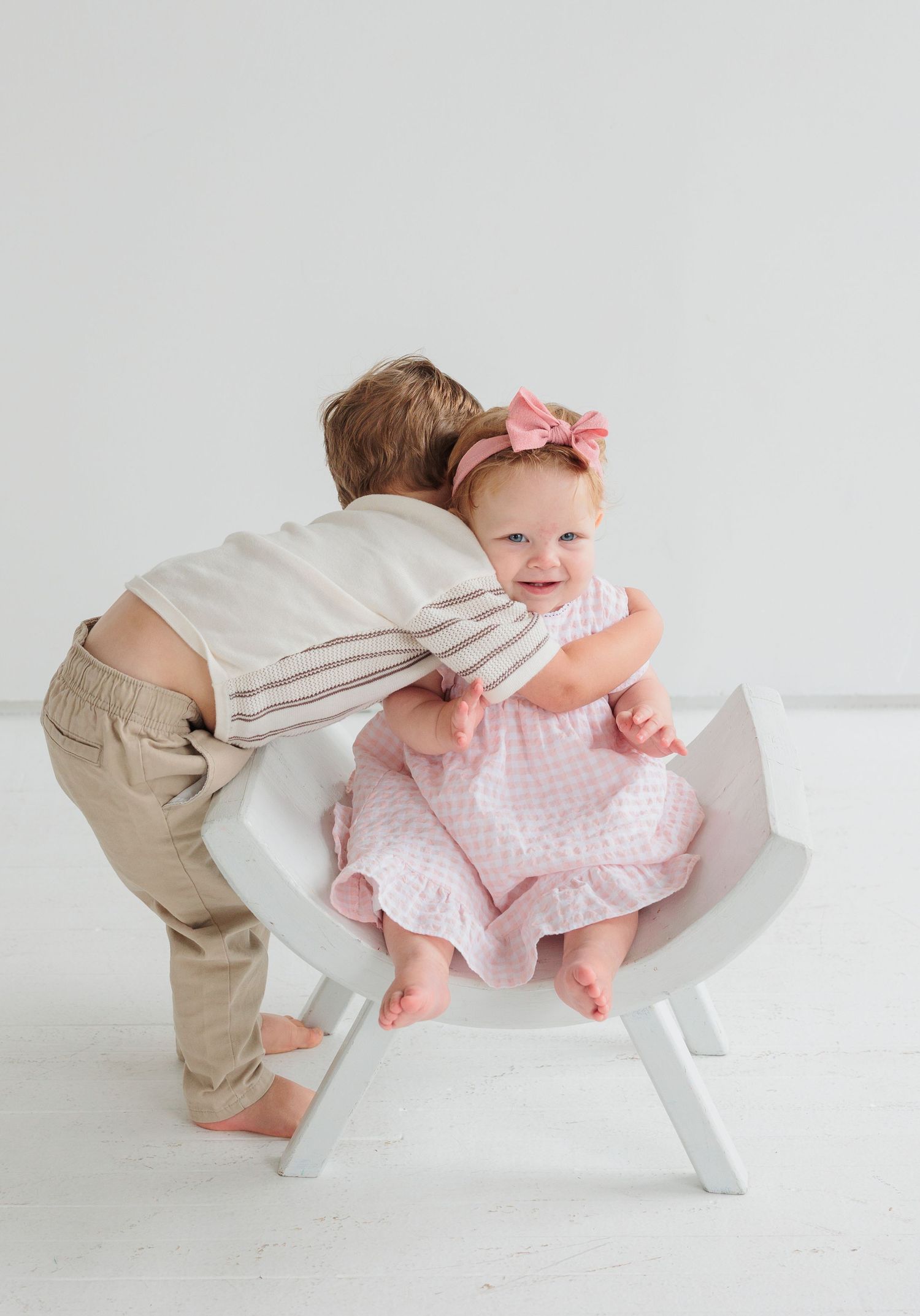 Two young children interact sweetly on a white chair against a light background.

Rochester NY wedding photographer