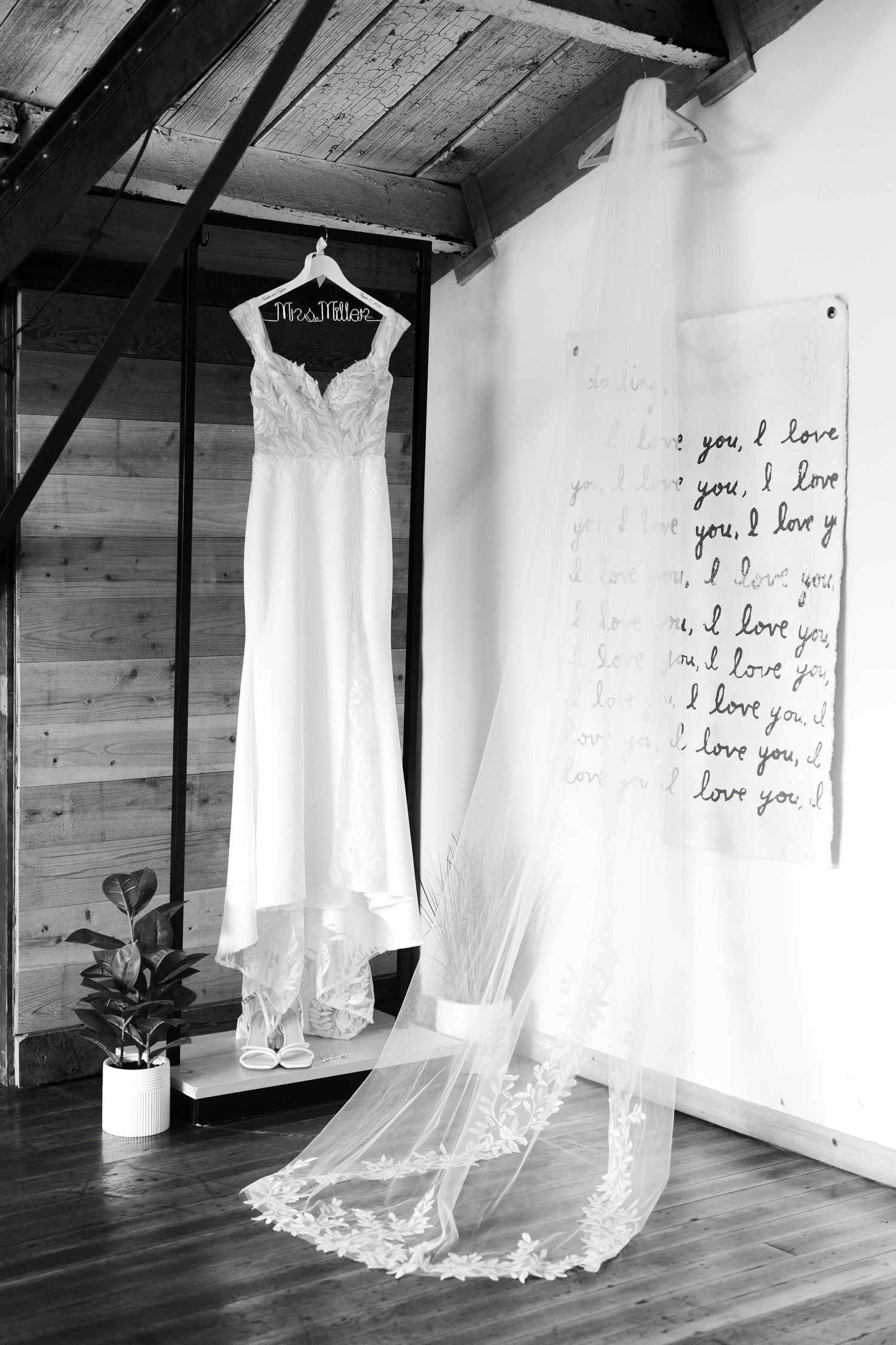 Wedding dress hanging in rustic room with handwritten love notes on wall.