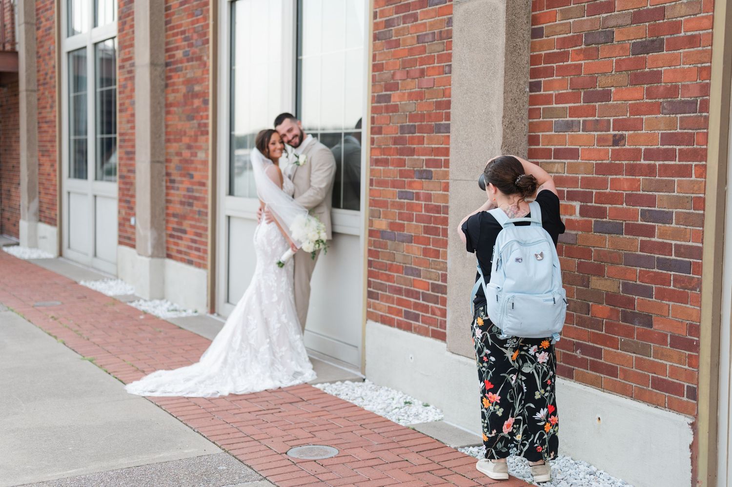 Wedding photography session outside a classic brick building with white trim windows.