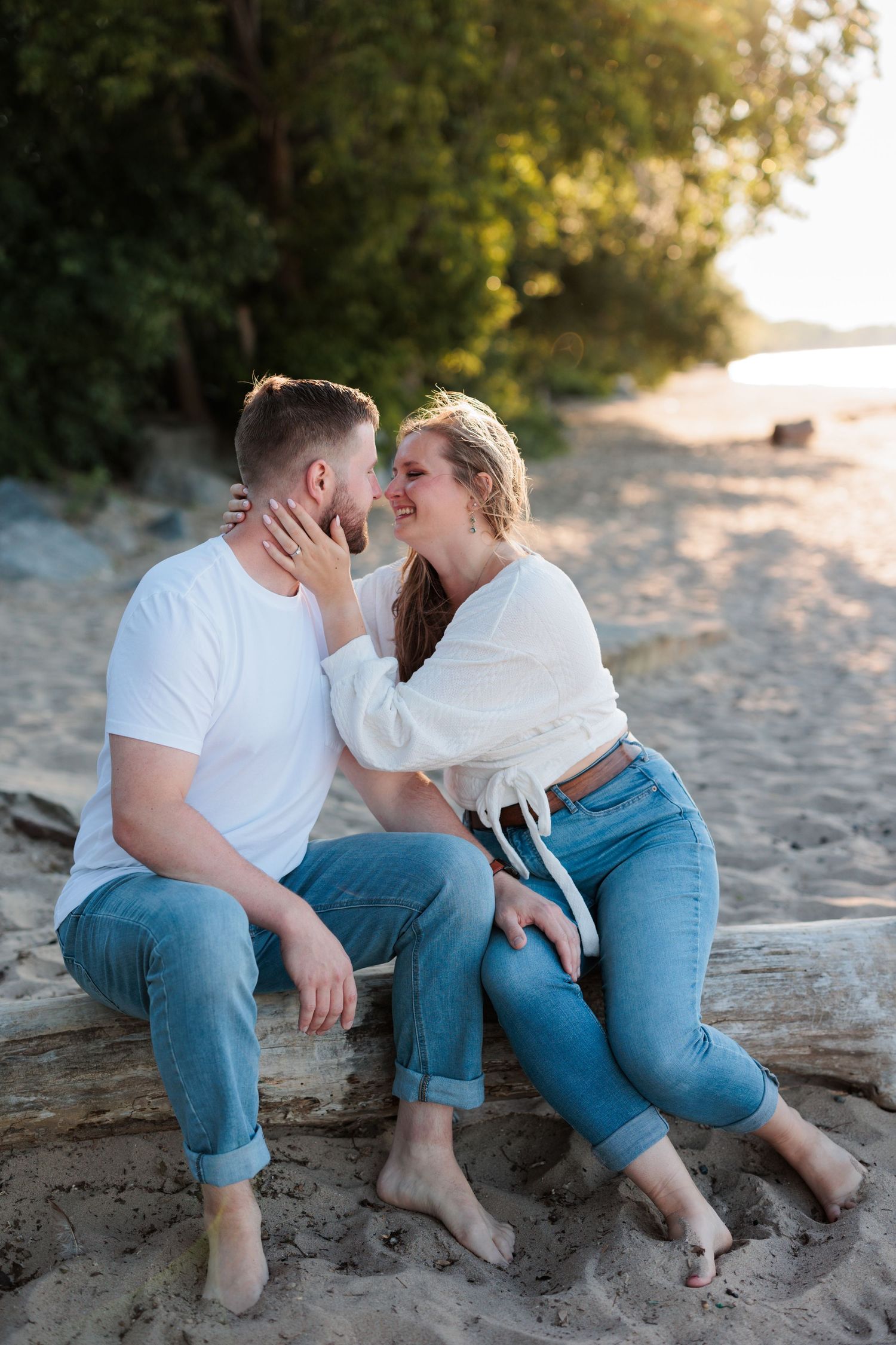 Couple shares romantic moment while sitting on sandy beach at sunset.