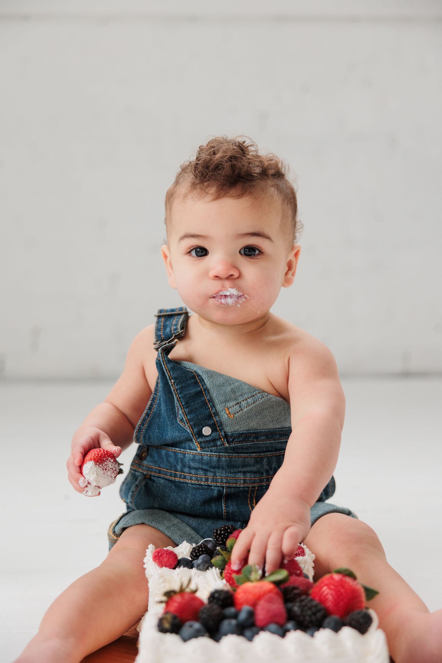 A baby in denim overalls enjoys berries and cream dessert.

Rochester NY wedding photographer