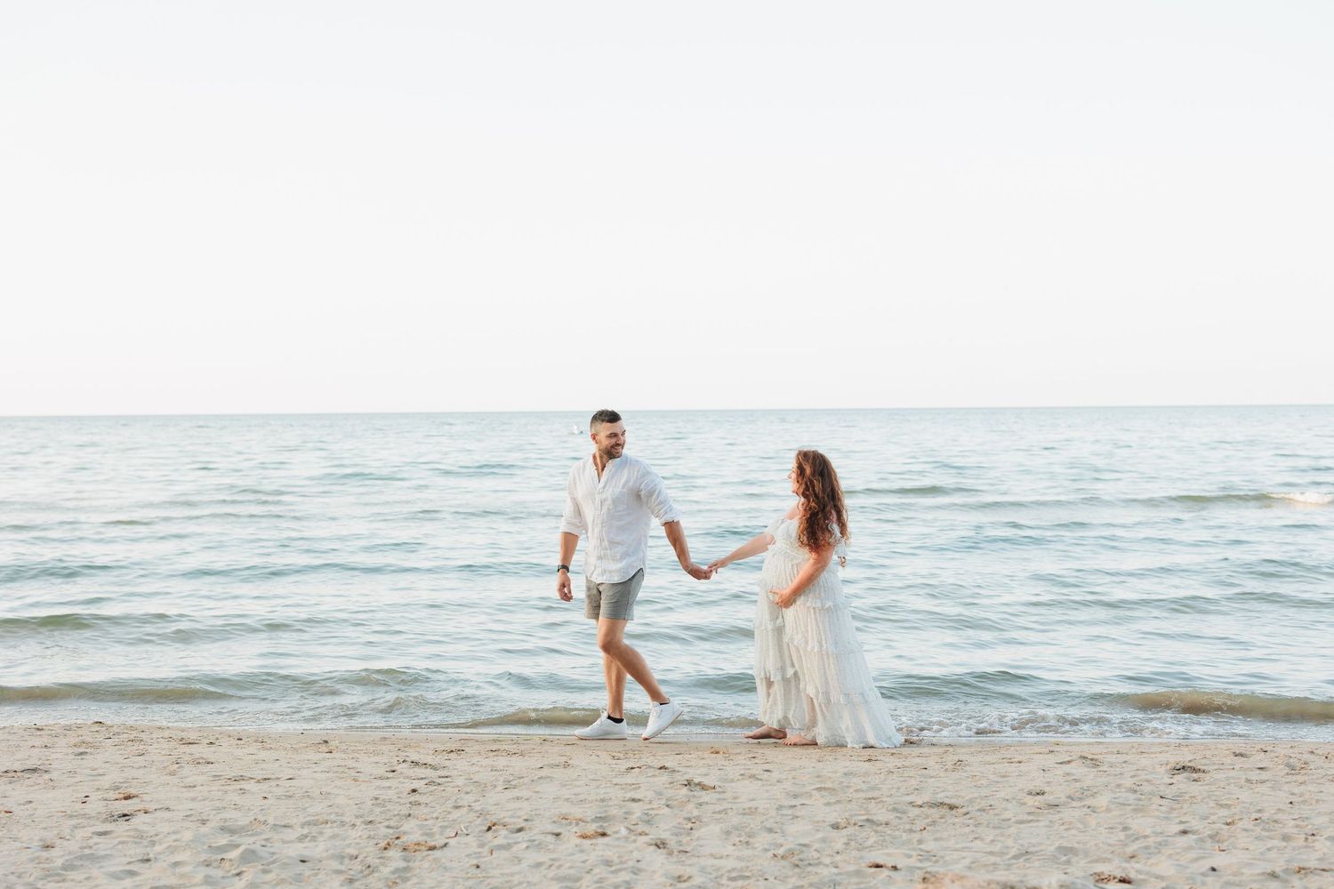 A romantic couple strolls along the beach shoreline in white summer outfits.

Rochester NY wedding photographer