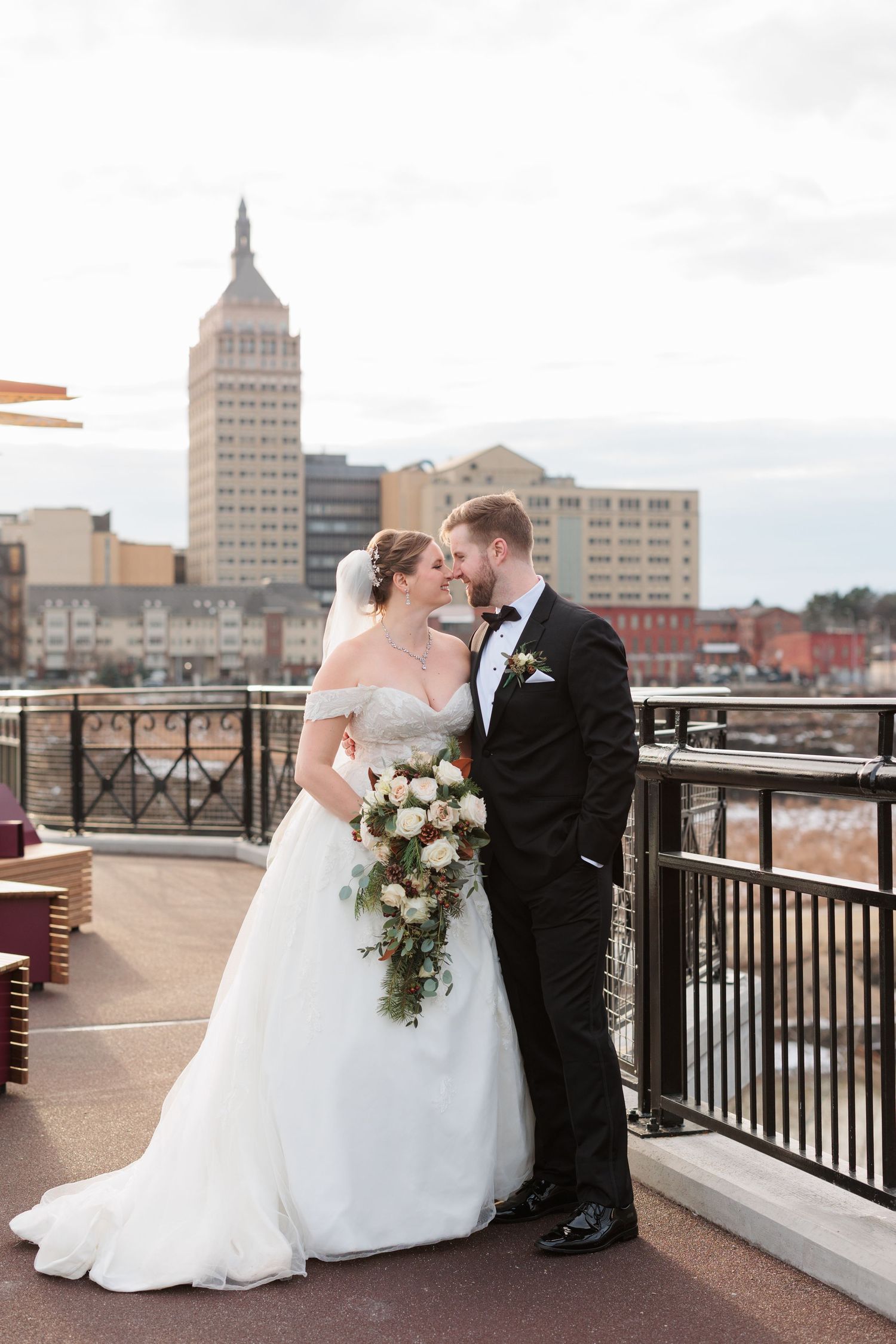 Romantic rooftop wedding photos with city skyline backdrop and elegant white dress and black tuxedo.