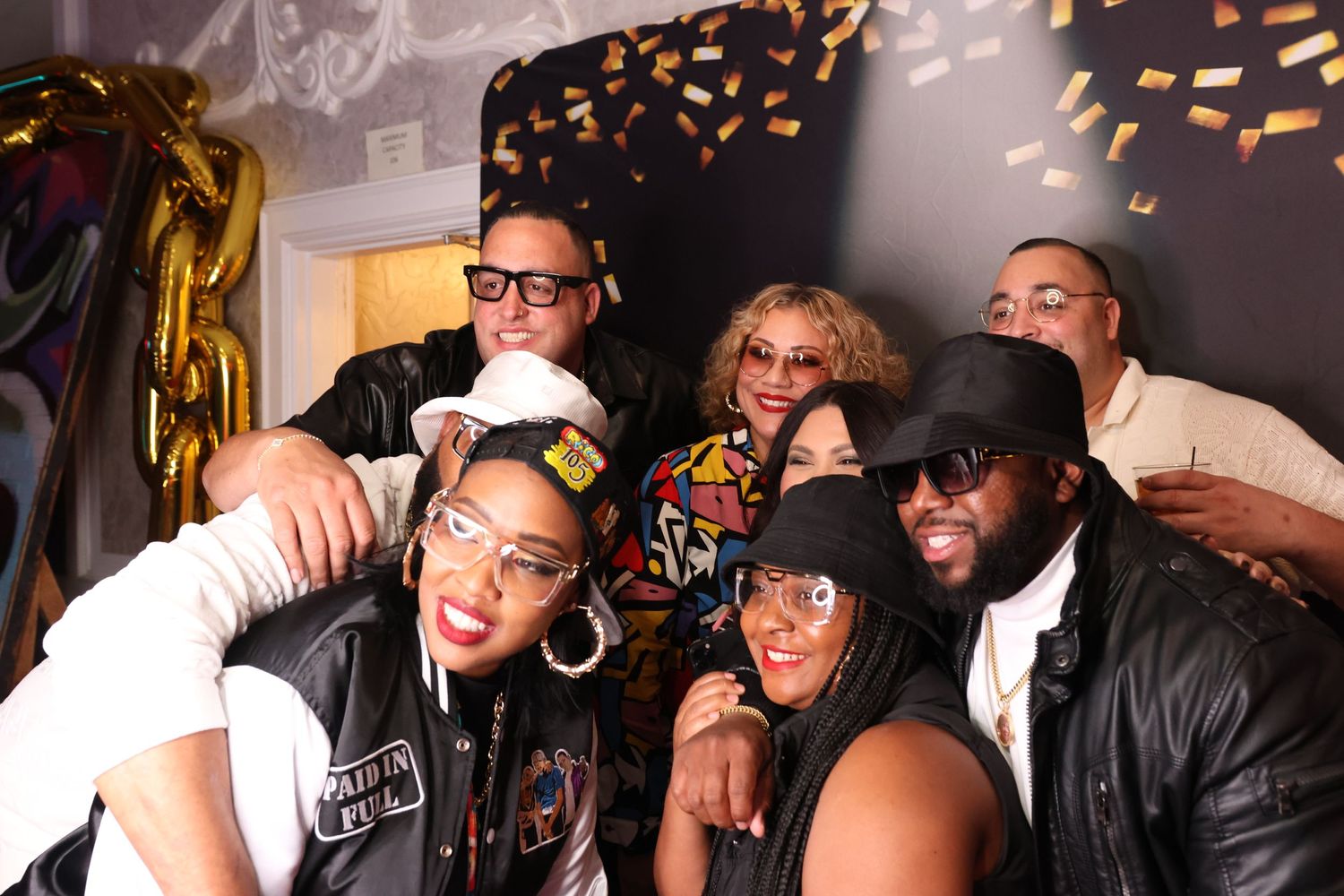 Group of friends having fun and posing together in a photo booth with party decorations.