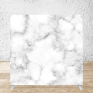 A large white marble backdrop with subtle gray veining patterns on a wooden floor against a white brick wall.