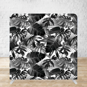 Black and white tropical monstera leaf pattern on display backdrop against white brick wall.
